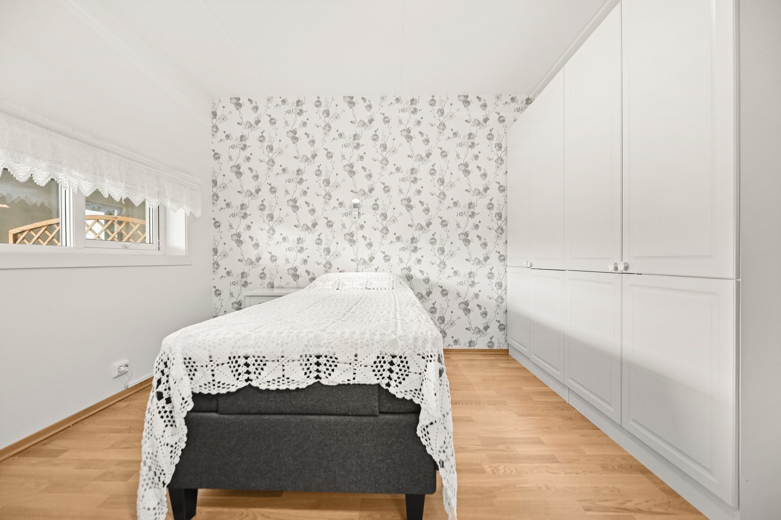 Lyst soverom med tapet på én vegg og innebygget garderobeskap. Galleribilde