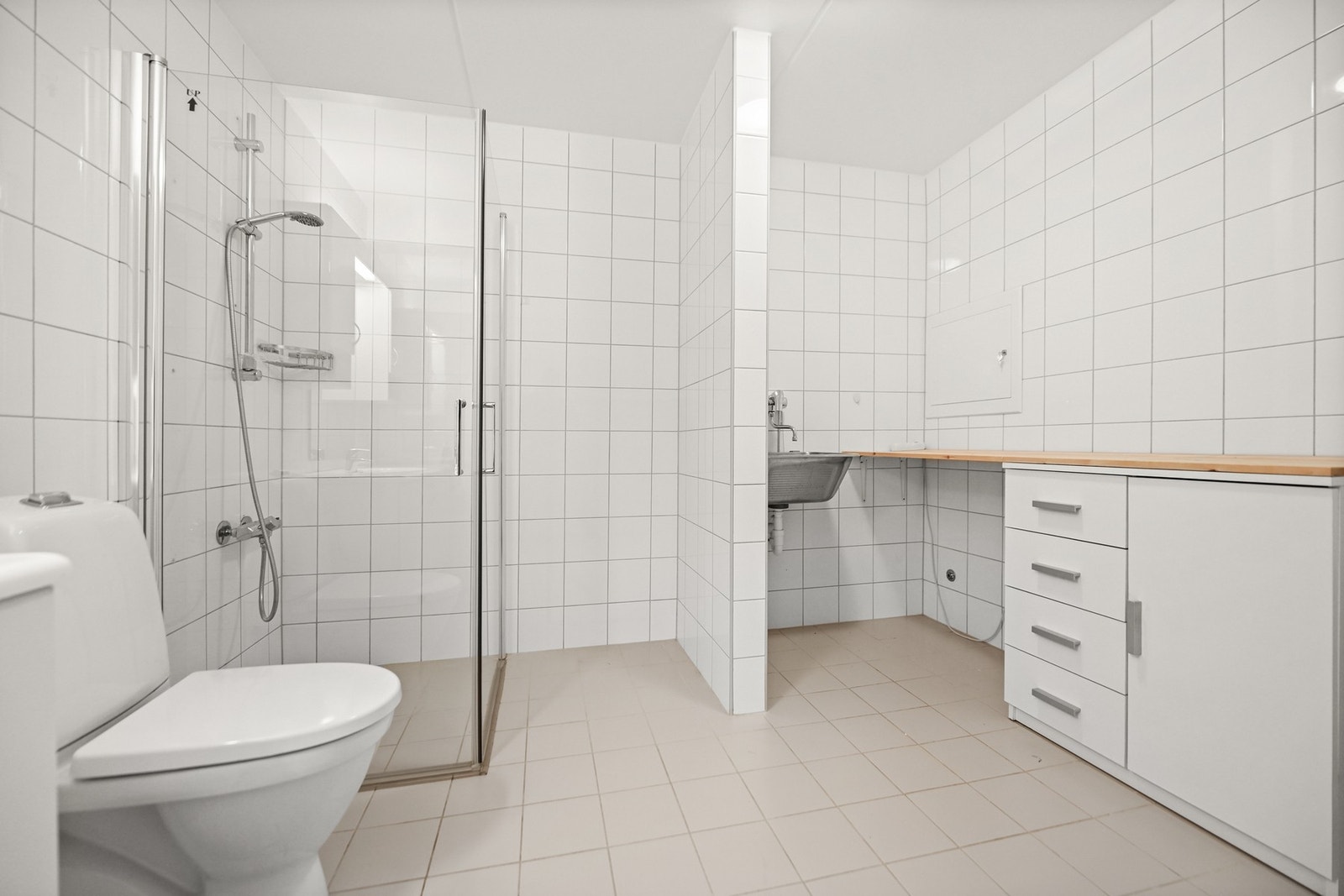 Flislagt bad med dusjhjørne, servant, toalett og oppbevaringsskap. Galleribilde