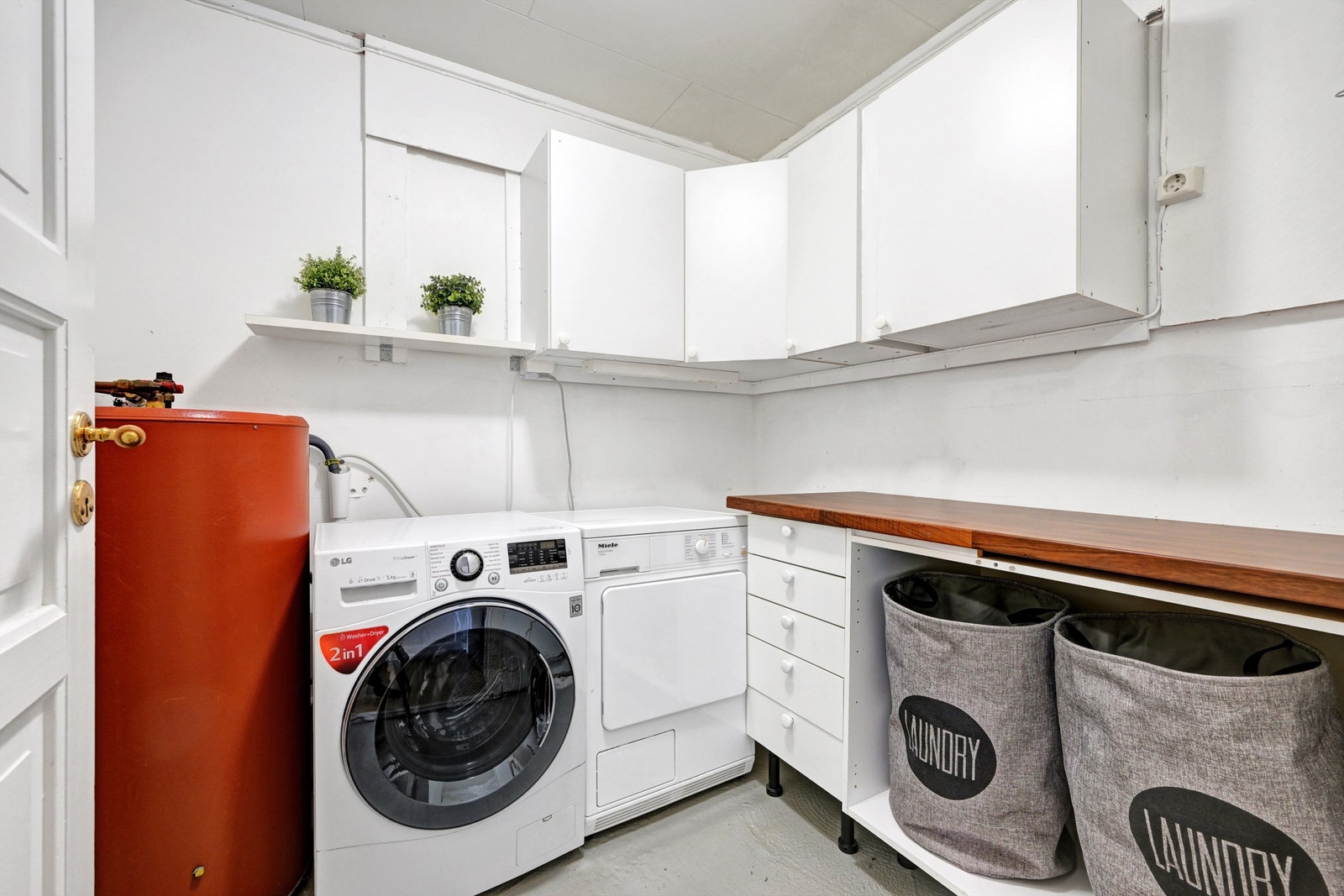 Vaskerom med opplegg til vaskemaskin, samt en benkeplate og praktiske skap for god lagringsplass. Galleribilde