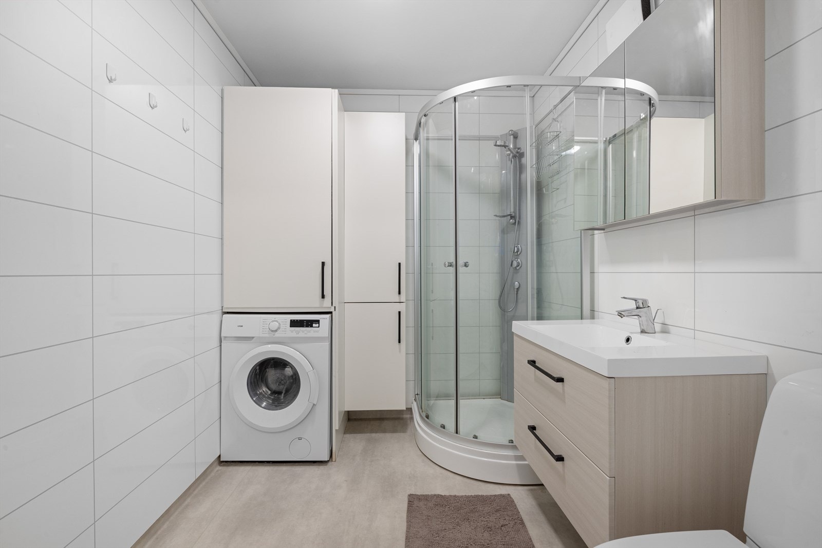 Det er høyskap ved vaskemaskin for praktisk oppbevaringsplass Galleribilde