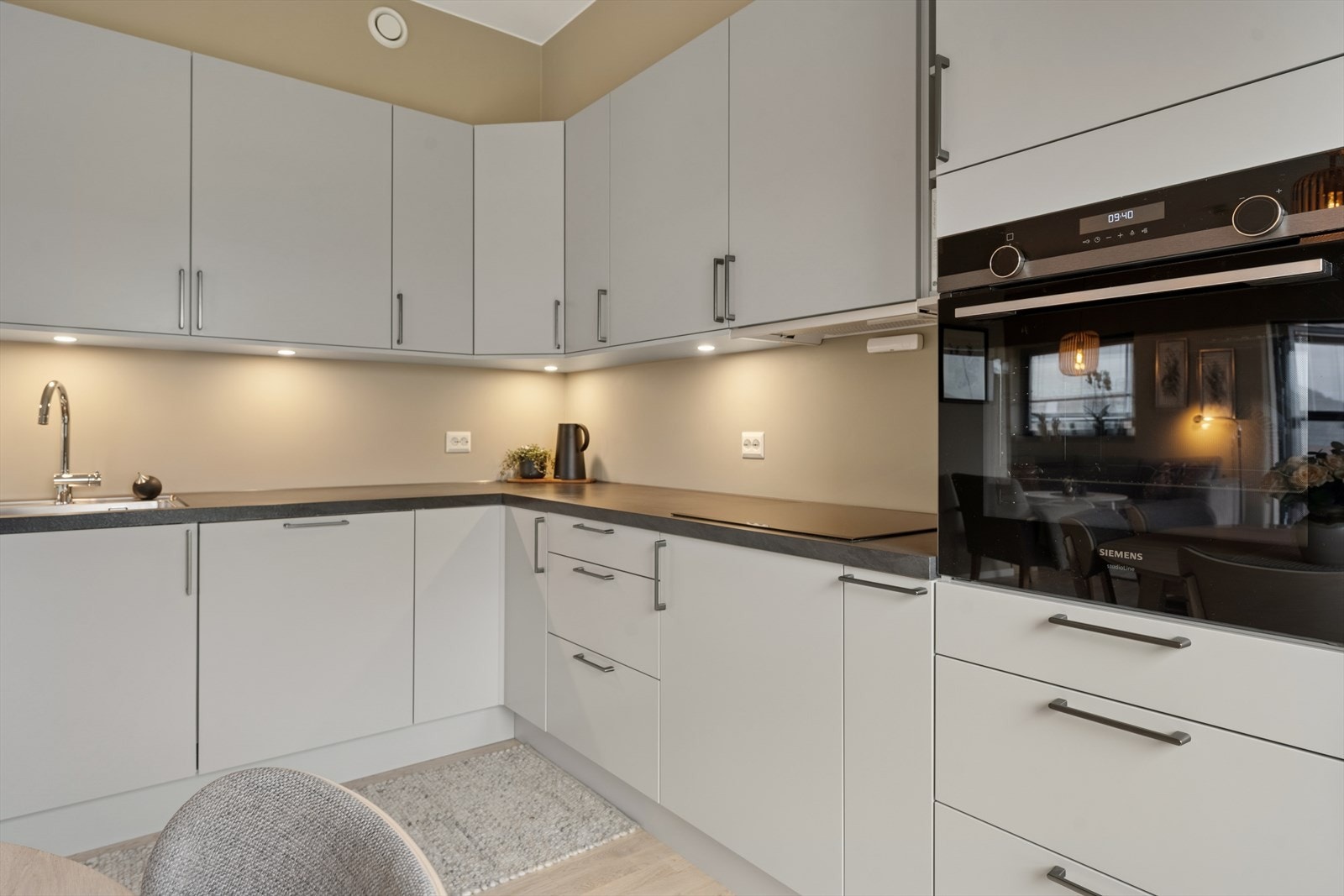 Den L-formede innredningen har takoppforede, glatte fronter og benkeplate av laminat. Galleribilde