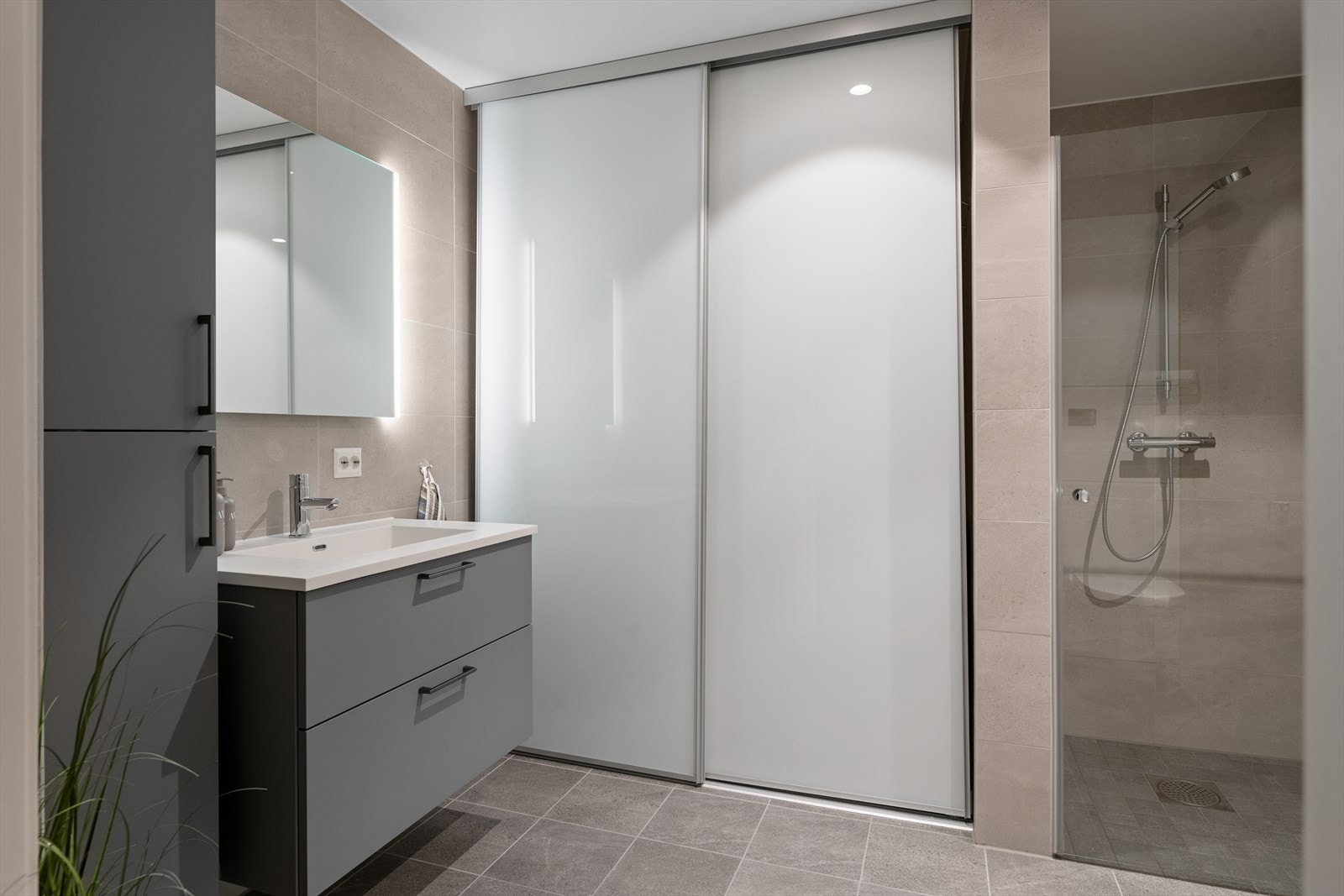 Badet er utstyrt med innredning med nedfelt servant, veggmontert toalett, dusjnisje med glassdør og opplegg for vaskemaskin. Galleribilde