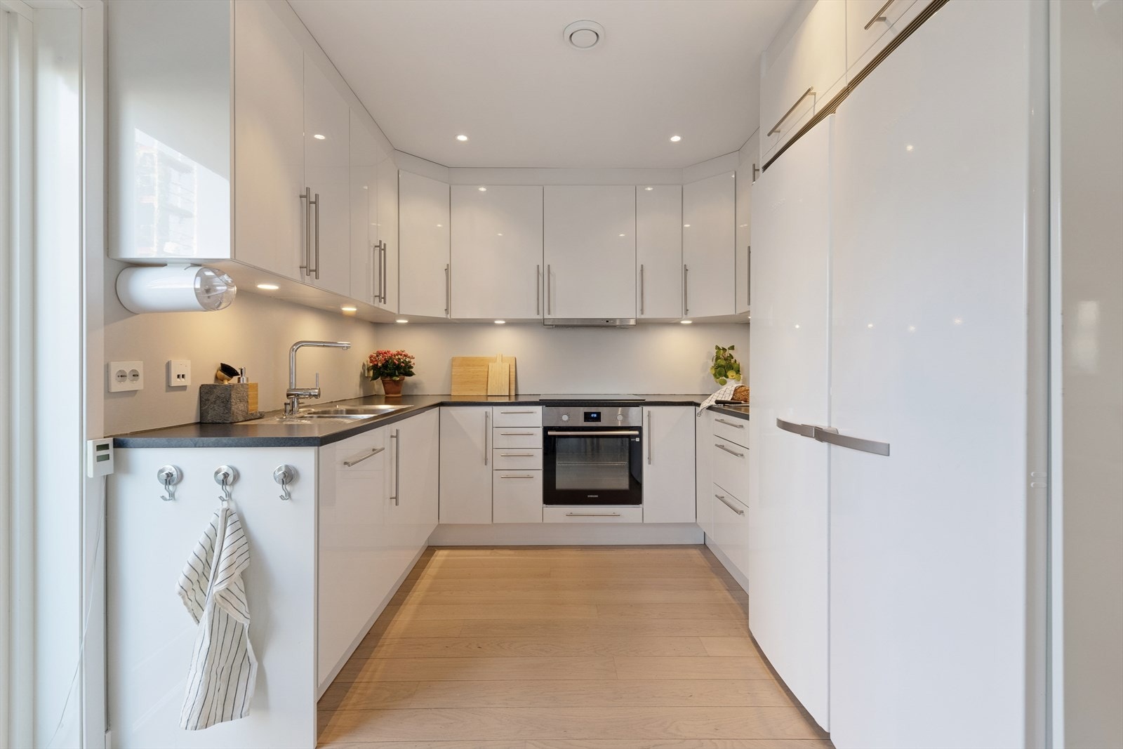 Kjøkkenet er stilrent innredet med hvite, slette fronter og grå benkeplate i laminat. Et stort og godt kjøkken hvor man har rikelig med lagringsplass og gode arbeidsflater på benk. Galleribilde