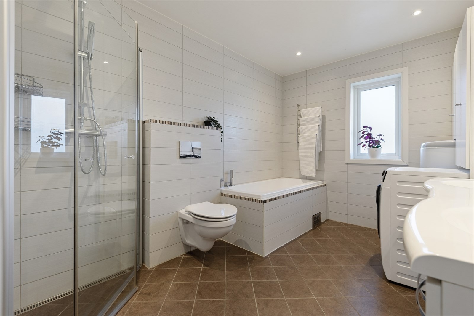 Badet er ellers utstyrt med dusjhjørne med innfellbare dører, badekar, vegghengt toalett og baderomsinnredning med nedfelt servant. I tillegg har man opplegg for vaskemaskin. Galleribilde