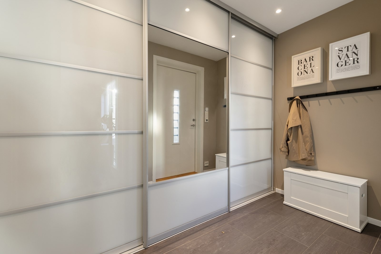 Man ønskes velkommen inn i en romslig entré som er praktisk innredet med flislagt gulv med varmekabler, og en stor skyvedrøsgarderobe som gir god lagringsplass til familiens klær og utstyr. Galleribilde