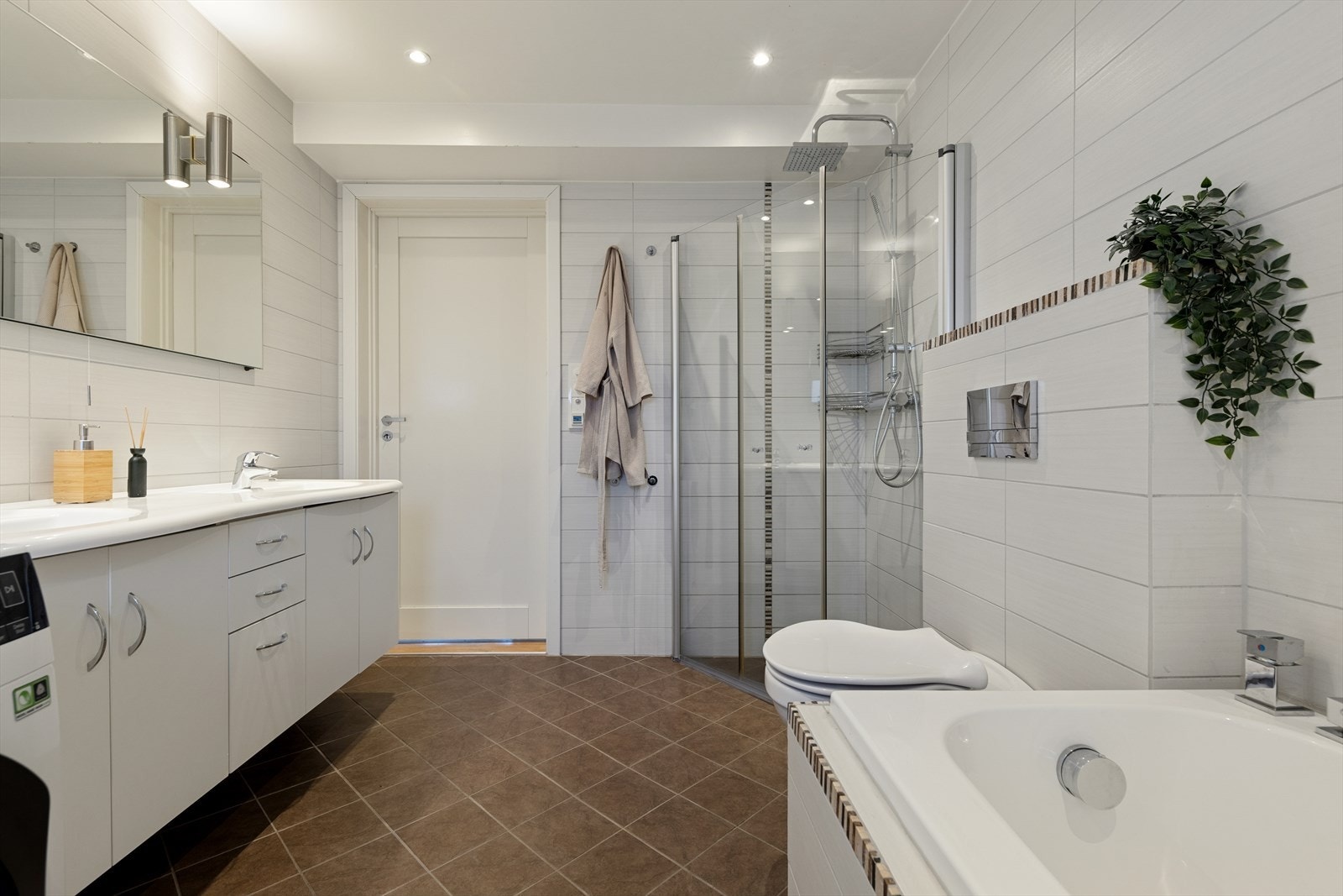 Baderommet i andre etasje er stort og helfliset med en kombinasjon av mørke og lyse fliser. Også her har man varmekabler. Galleribilde