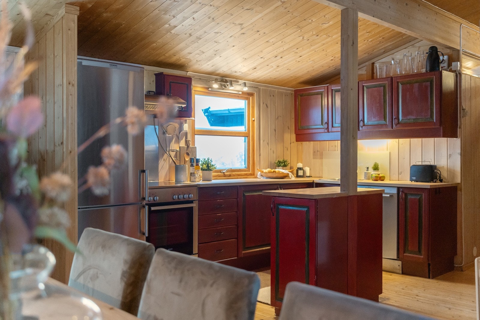 Hytta sitt store kjøkkenrom har åpen løsning til en romslig spisestue med peis Galleribilde