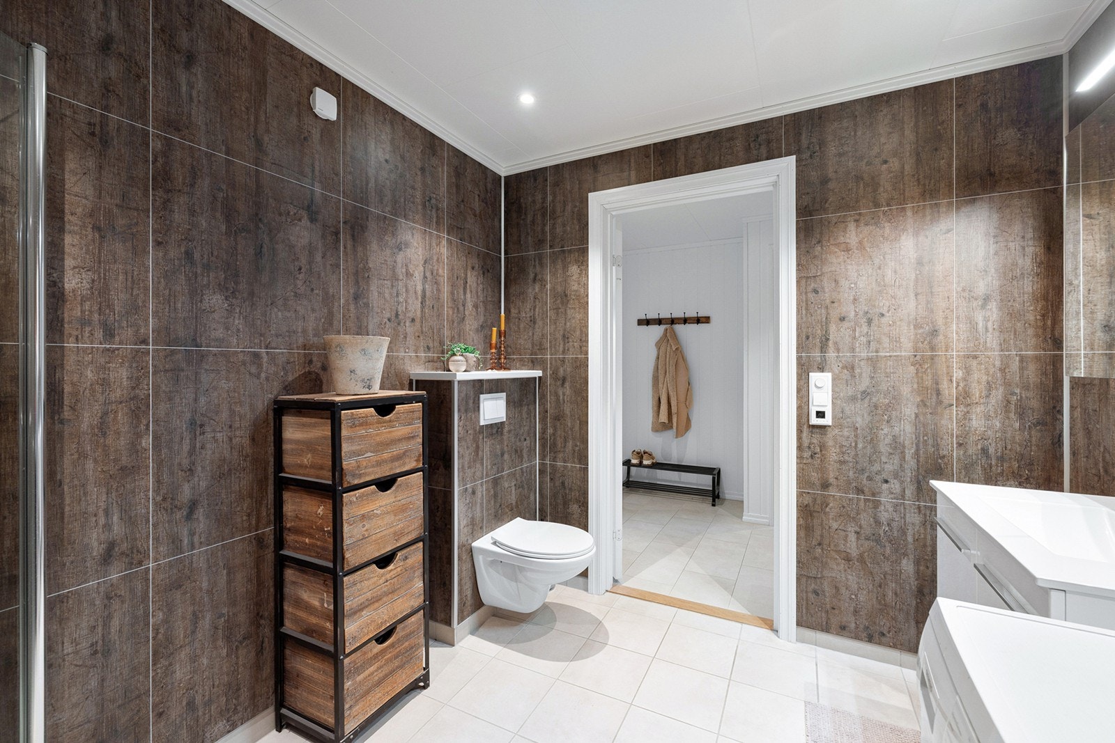 Badet har dusjhjørne med glassvegger, vegghengt toalett, servantmøbel samt opplegg for vaskemaskin og tørketrommel. Galleribilde