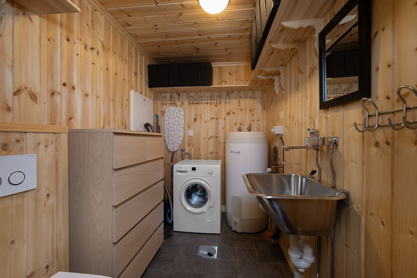 Praktisk vaskerom med flislagt gulv med gulvvarme, opplegg for vaskemaskin og vegghengt toalett. Galleribilde