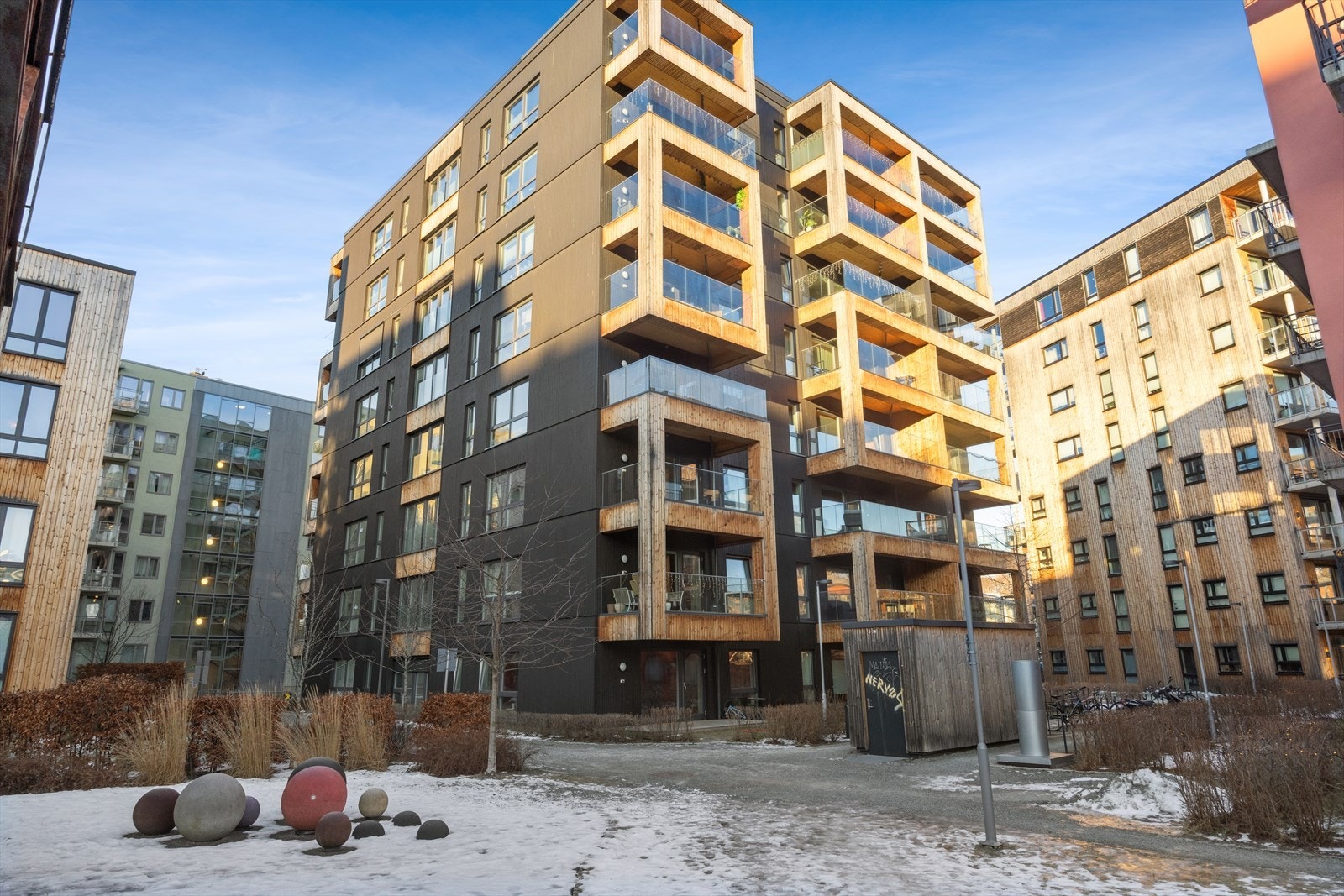 Tiltalende bygninger med innslag av treverk som bryter opp fasadene. Galleribilde