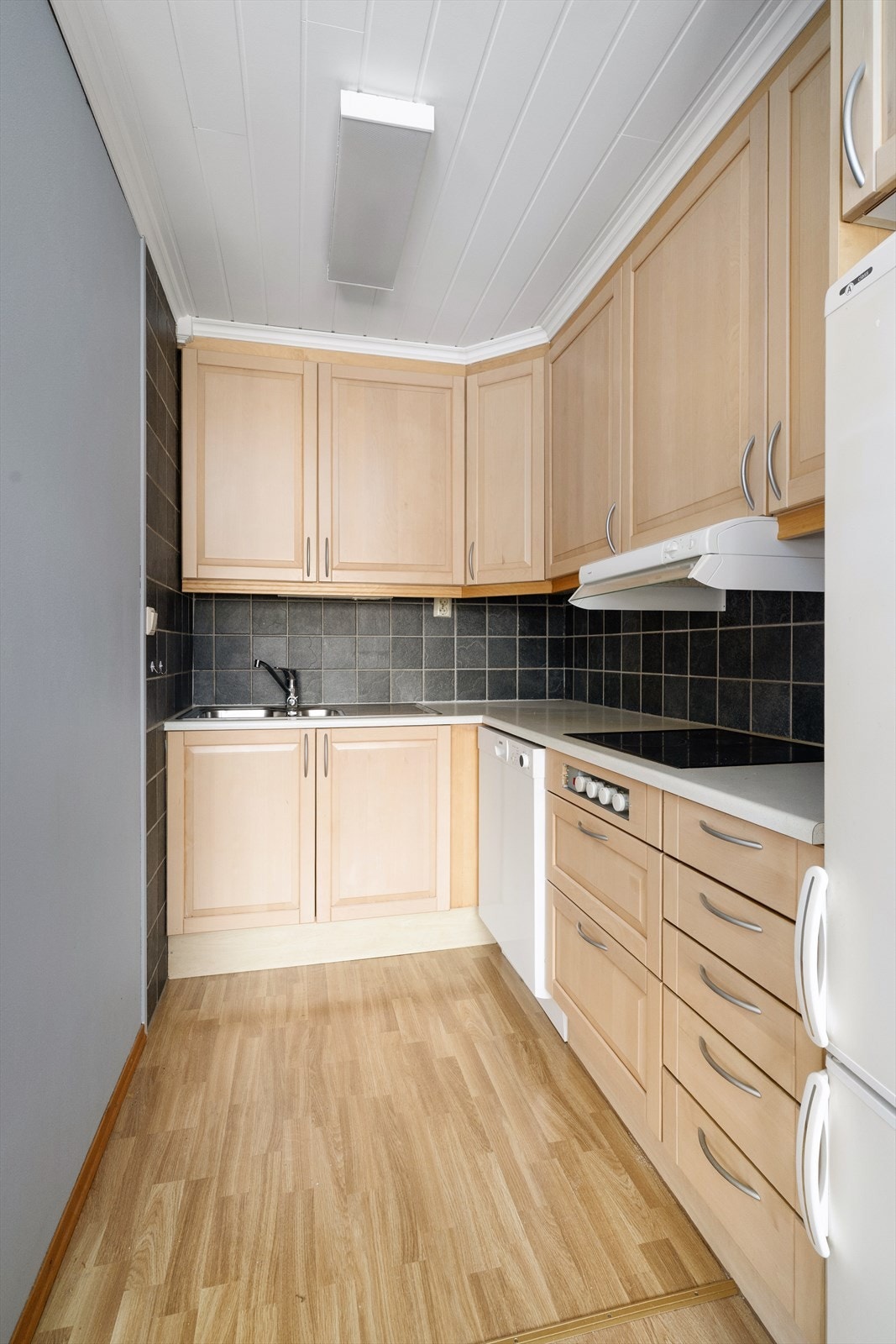 Kjøkkenet har innredning med profilerte fronter og benkeplate av laminat med flis over. Det er god oppbevaringsplass i over- og underskap, samt i skuffer. Integrert platetopp og stekeovn, samt opplegg for oppvaskmaskin. Galleribilde