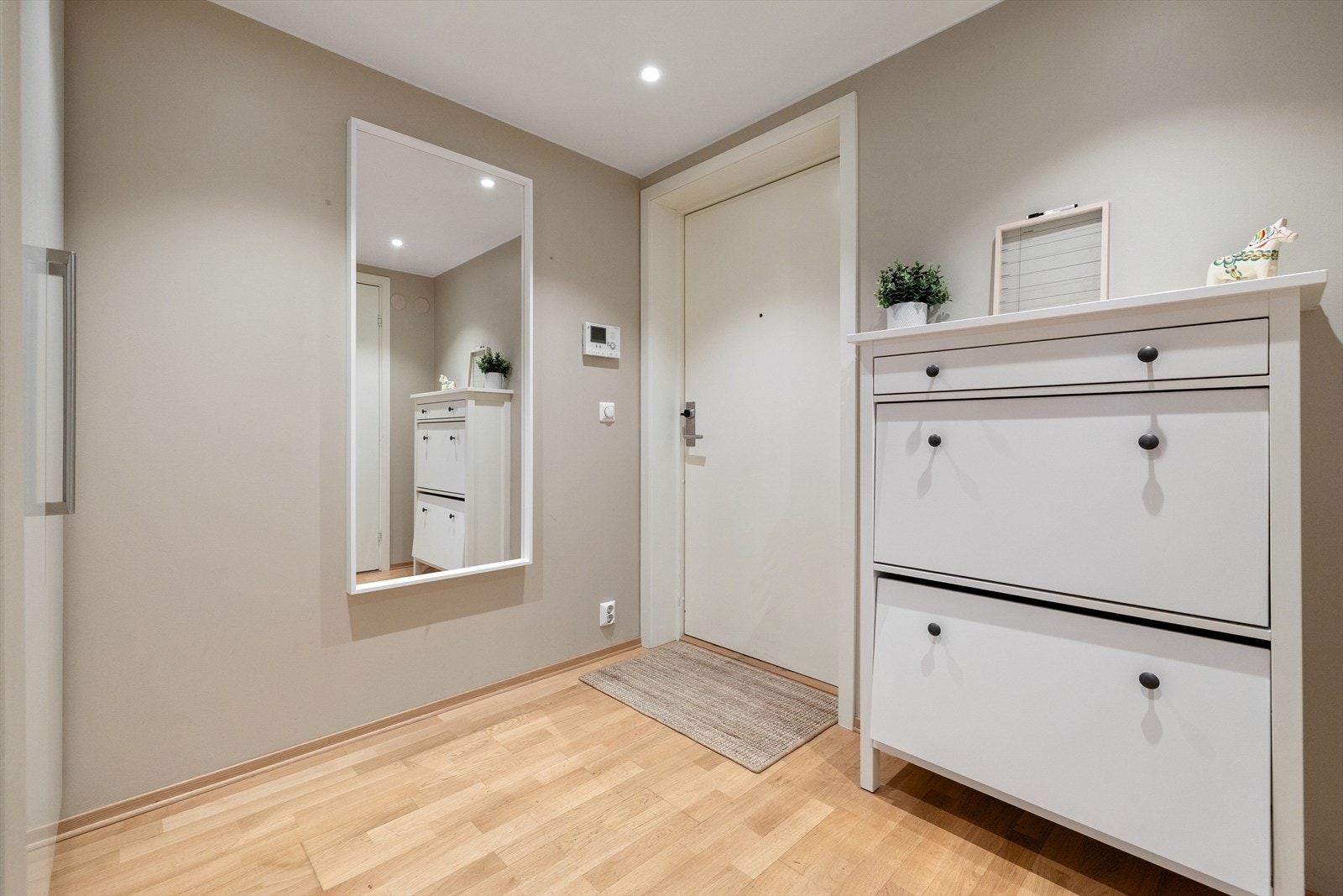 Velkommen inn. Entréen er romslig og har godt med lagring i sko- og garderobeskap. Leiligheten har installert callinganlegg med kamera for å slippe inn gjester. Galleribilde