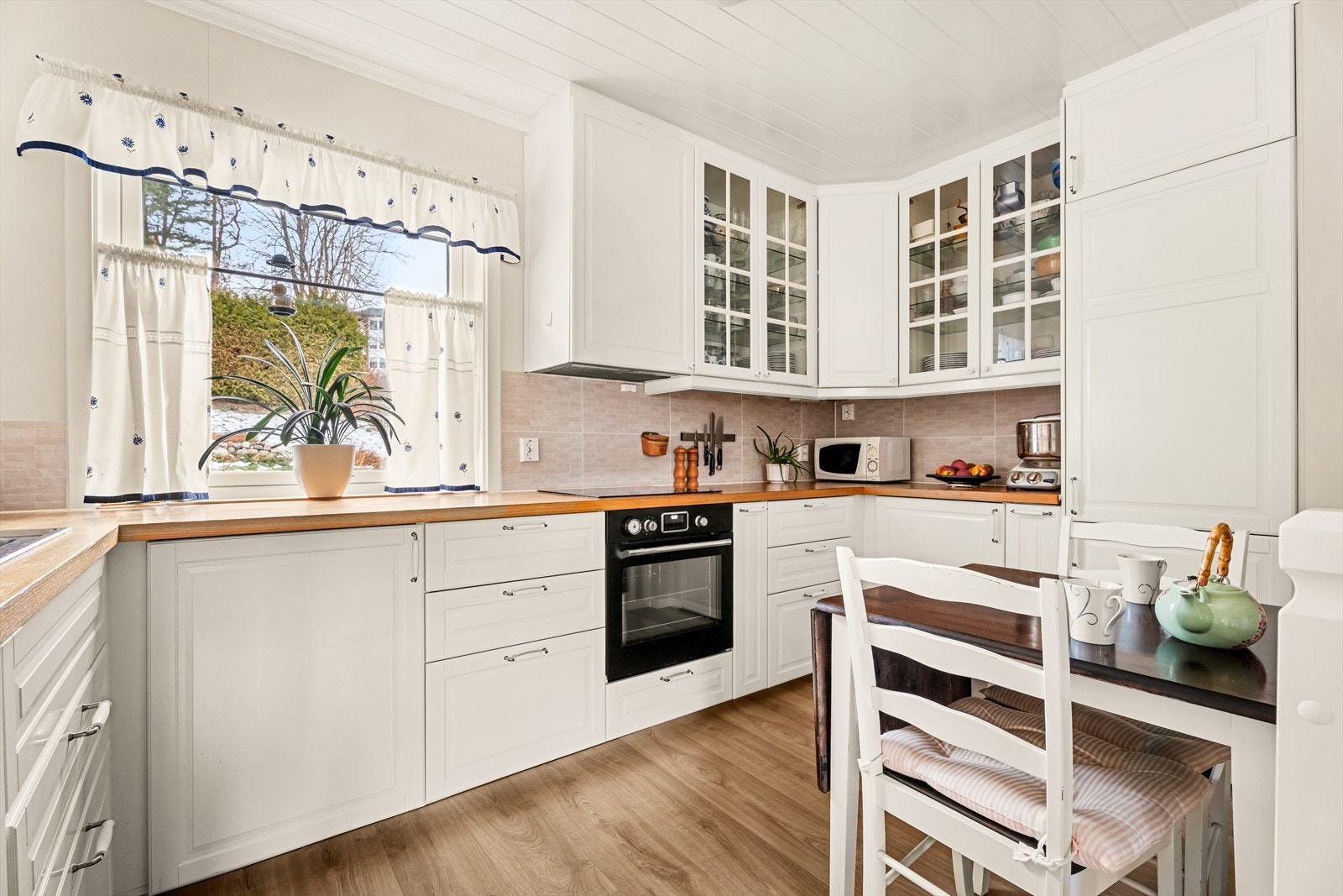 Kjøkkenet ligger i 2. etasje og ble montert nytt i 2024. Innredning fra IKEA med hvite profilerte fronter, laminert benkeplate og oppvaskkum. Det er fliser mellom benk og overskap. Galleribilde