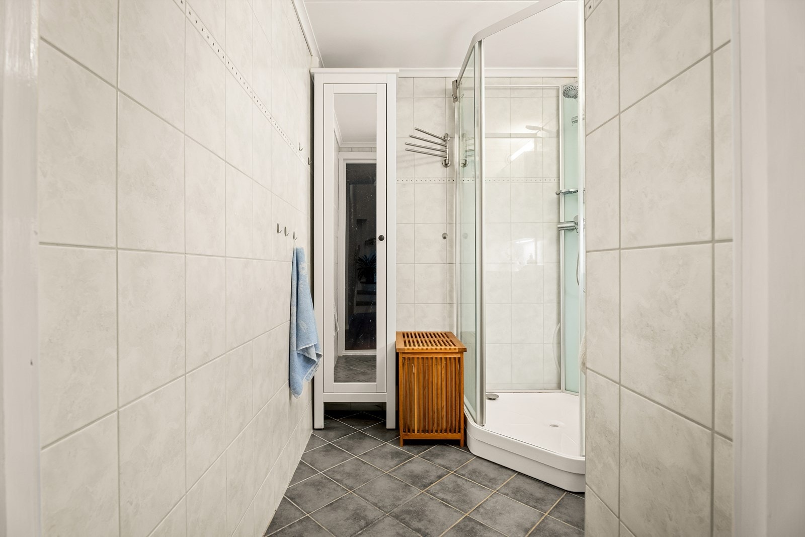 Badet har fliser på gulv og vegger samt malte plater i himling. Badet er utstyrt med servantinnredning, dusjkabinett og oppbevaringsskap. Det er elektriske varmekabler i gulv. Galleribilde