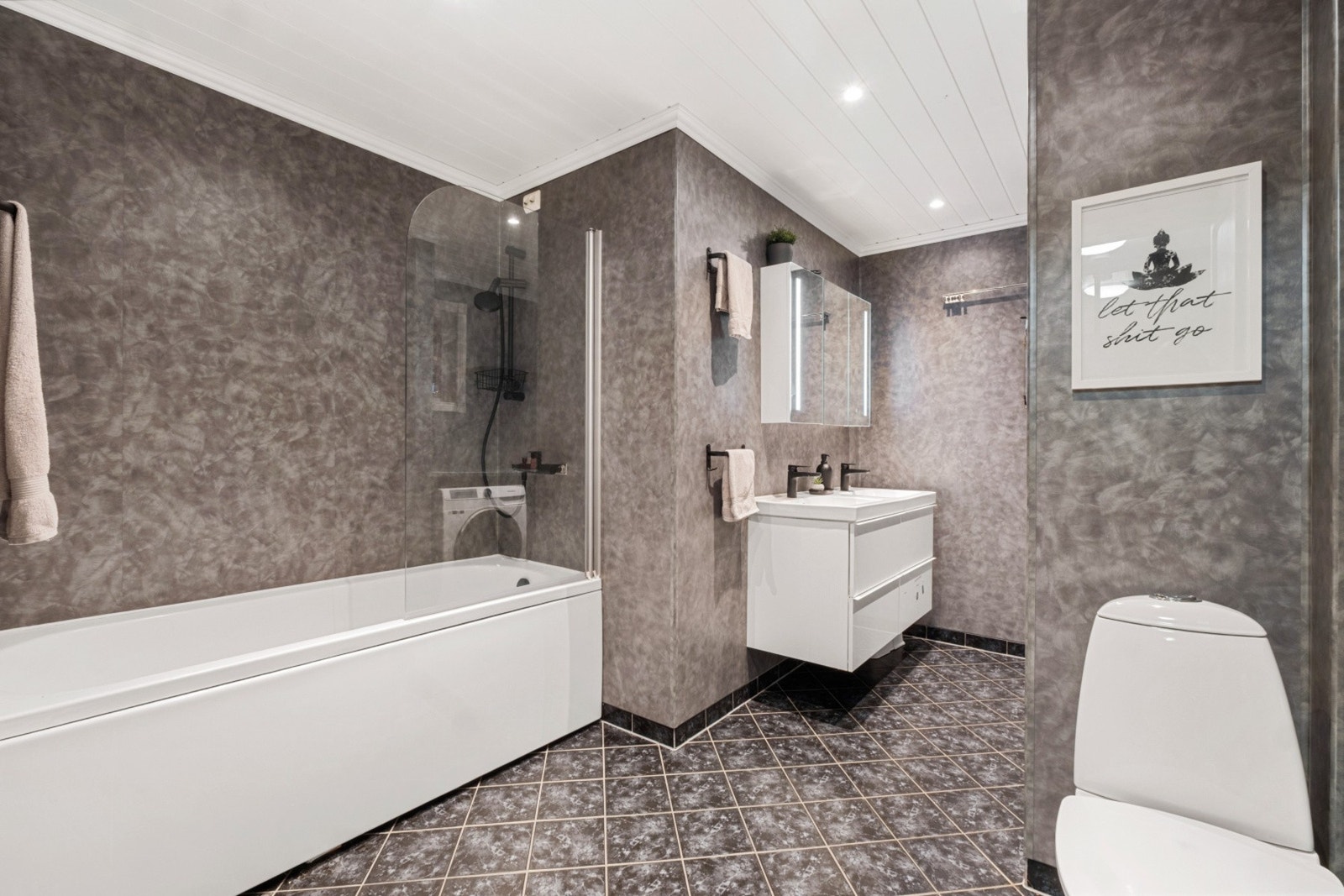 Bad med baderomsplater på veggene og flislagt gulv med varmekabler. Galleribilde