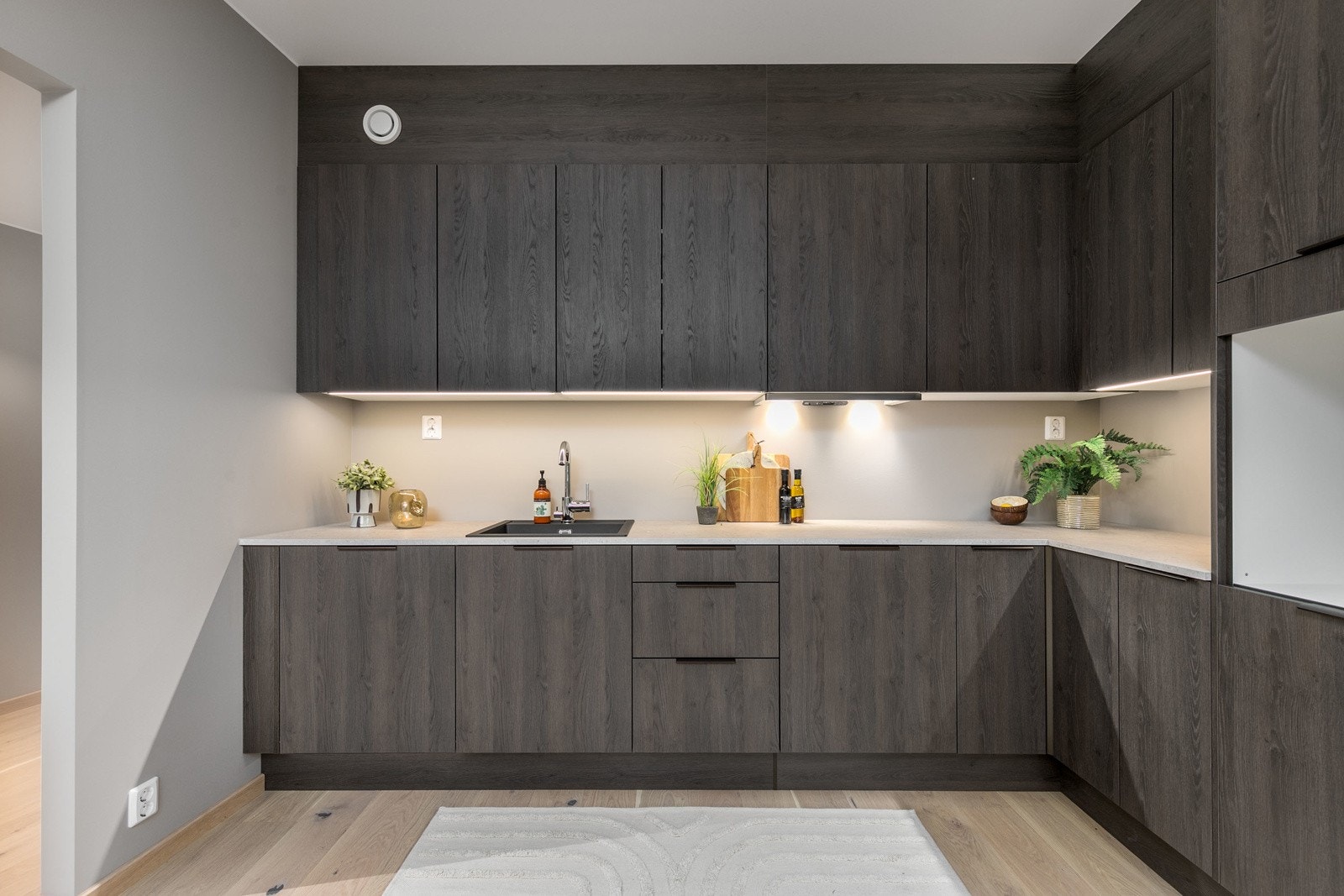 Kjøkkenet er utformet i praktisk vinkelform, som sørger for rikelig med skap og benkeplass Galleribilde