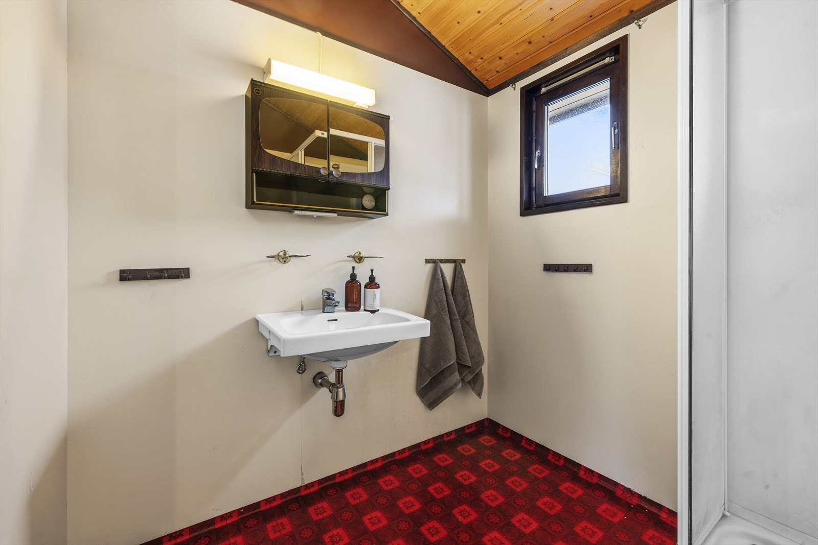 Baderommet er innredet med dusjkabinett og enkel servant på vegg Galleribilde