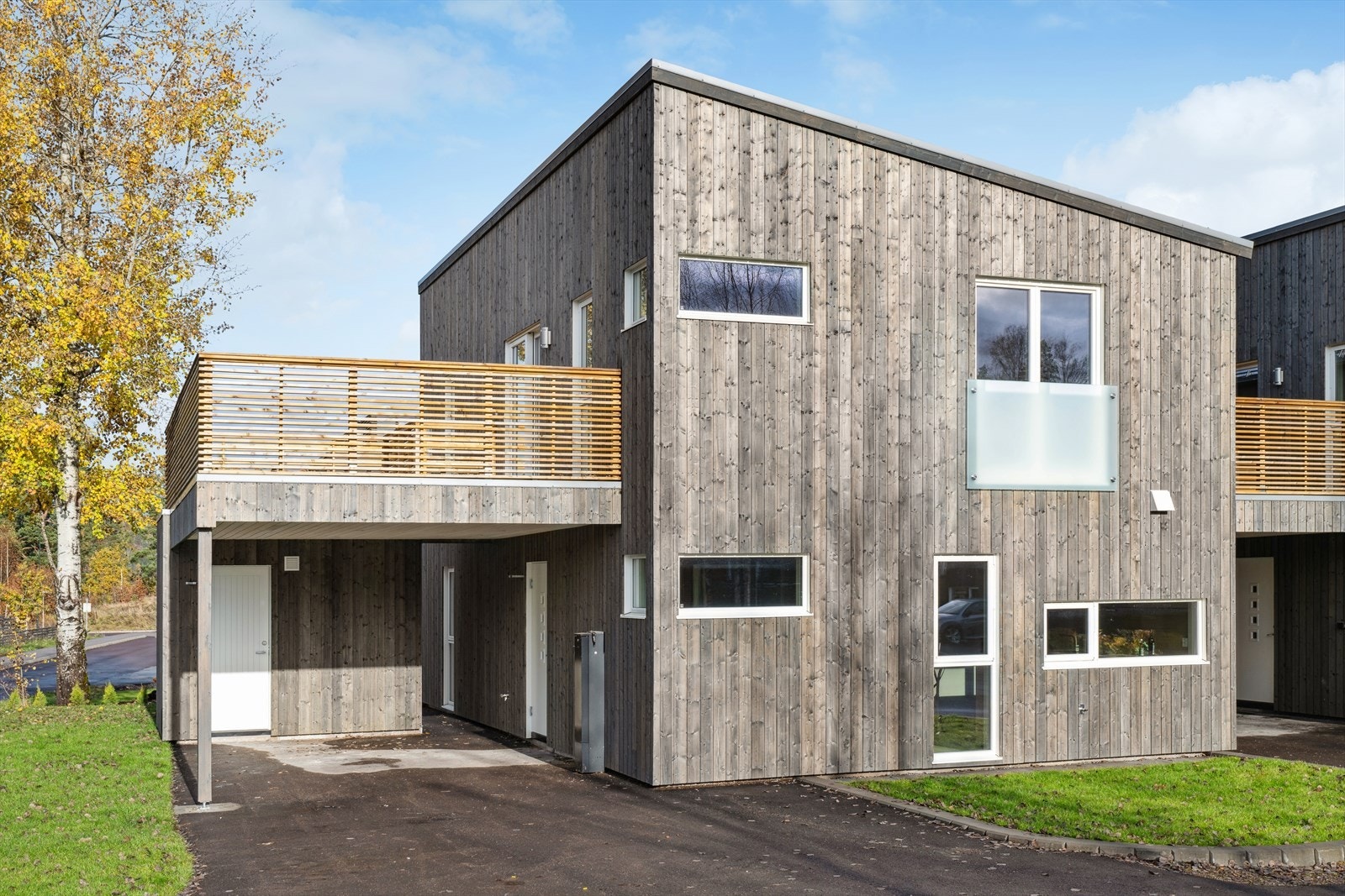 Pent opparbeidet uteområde med asfalterte flater rundt boligen og grønn, velstelt plen - enkelt og innbydende. Galleribilde