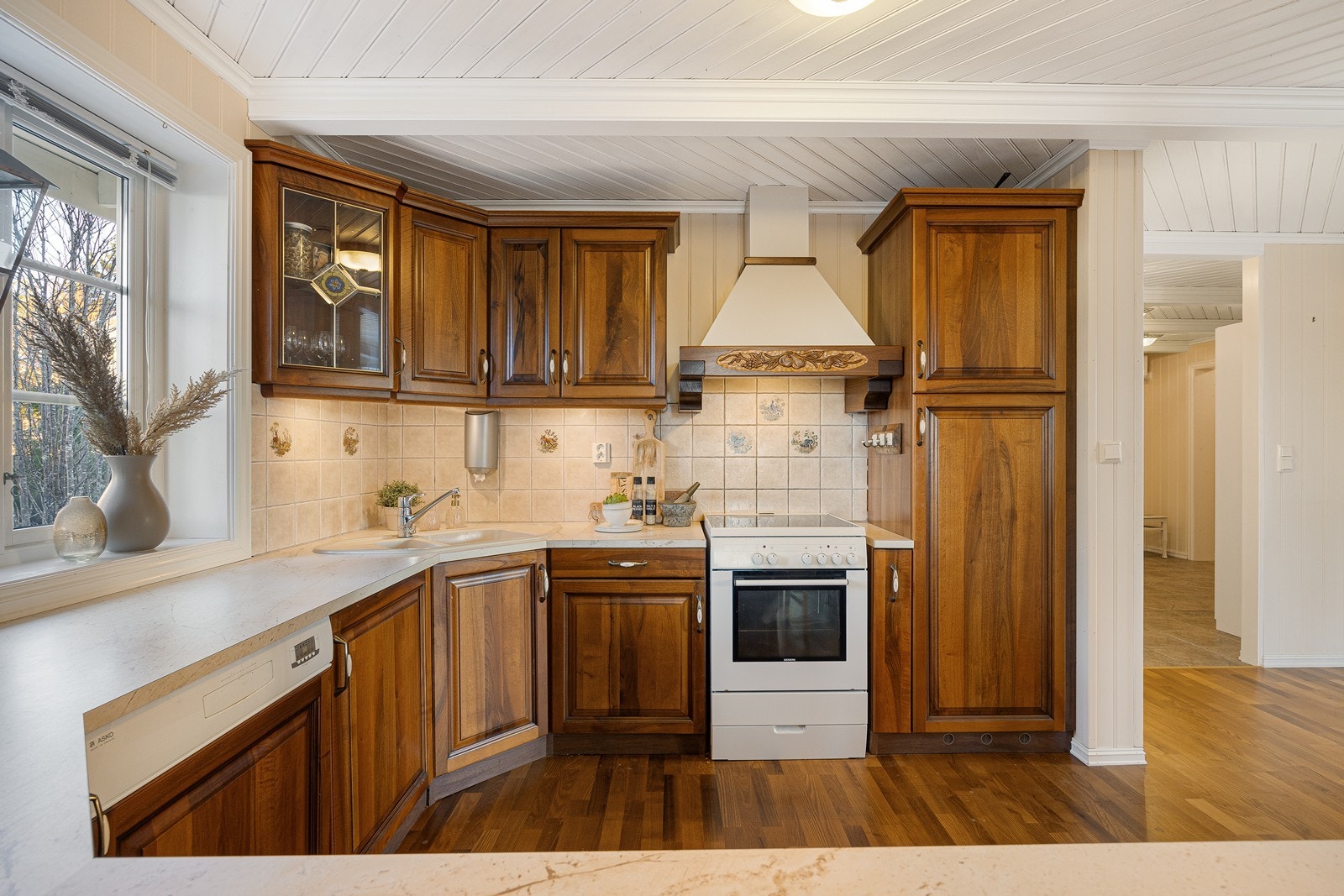 Innredningen har et klassisk uttrykk med profilerte heltrefronter, vakre vitrineskap, dobbel oppvaskkum og laminert benkeplate i marmormønster. Integrert i innredningen finner man kjøleskap og oppvaskmaskin. Galleribilde