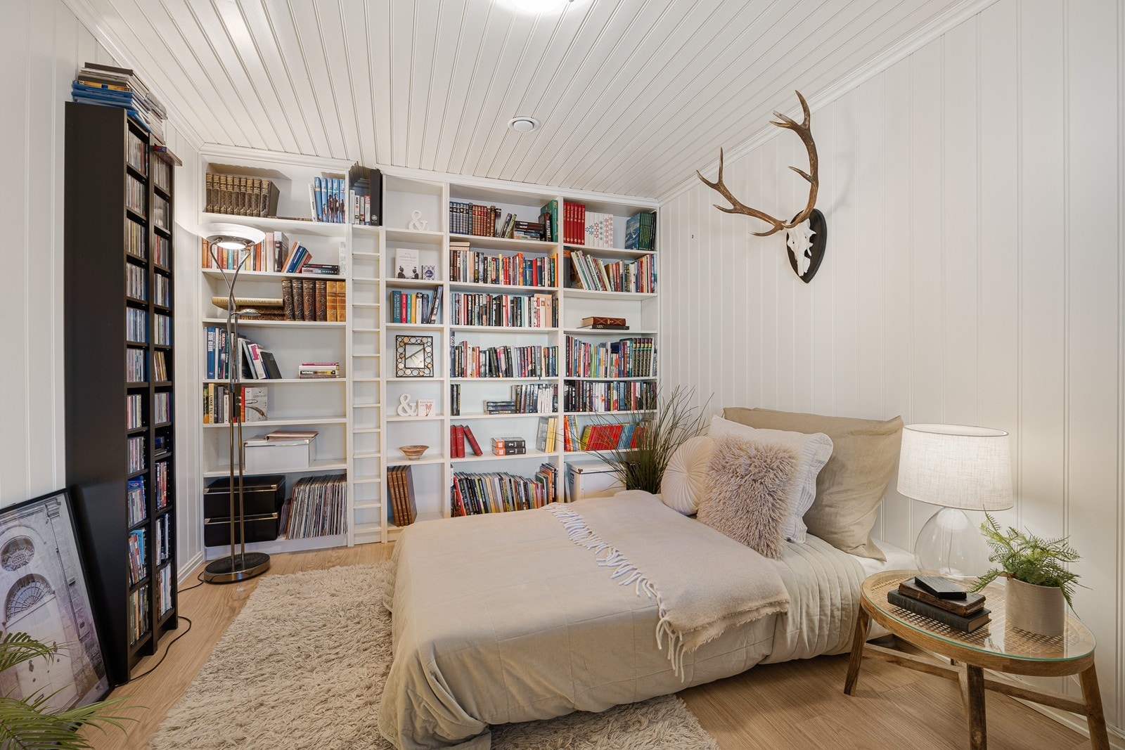 Langs den ene veggen har dette soverommet en stor hylleløsning for bøker, planter og annen dekor. Galleribilde