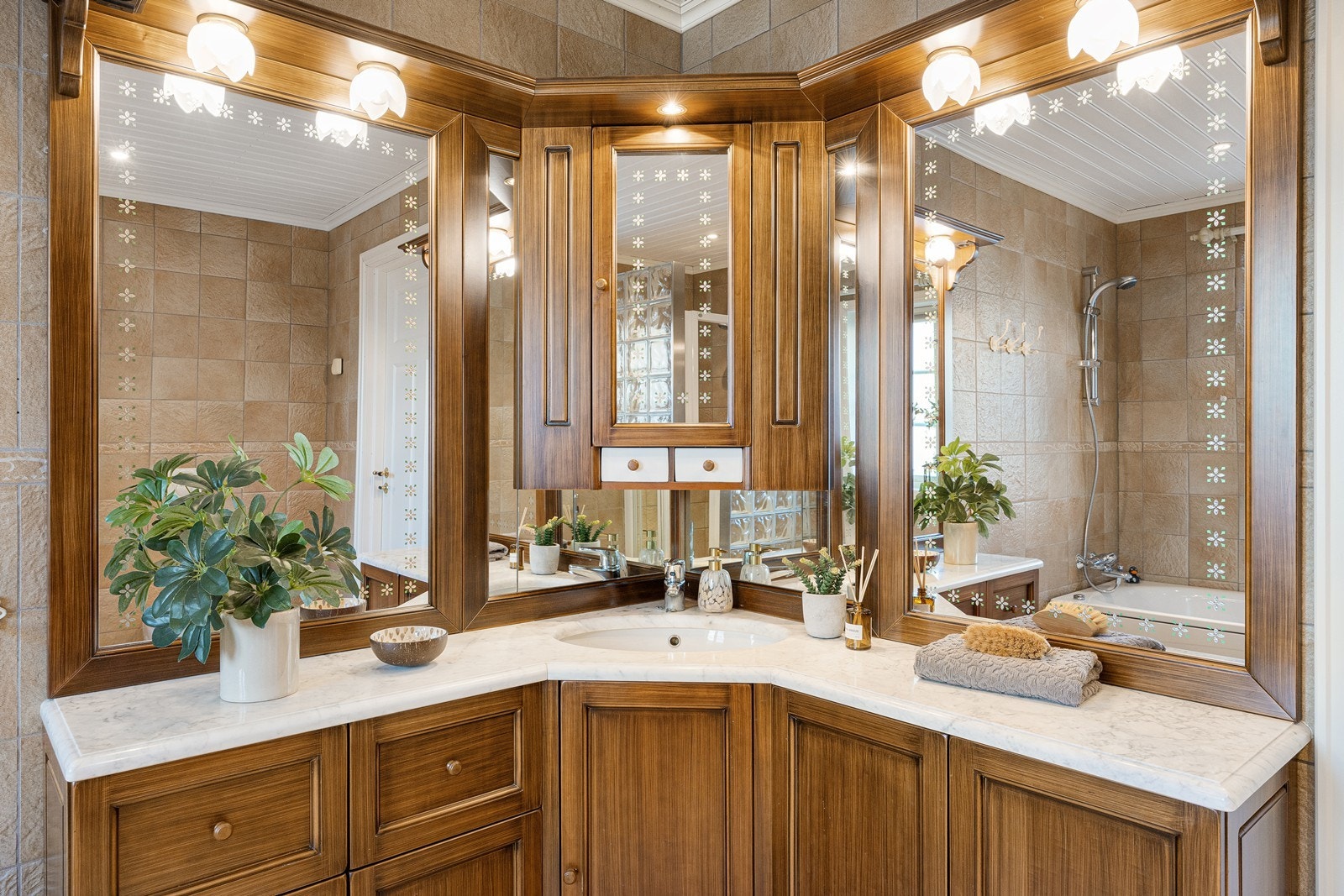 Baderomsinnredningen står i stil til huset for øvrig, bestående av et elegant hjørneskap med stor servantbenk og vakre speil på veggen - inkludert et speilskap med små skuffer. Galleribilde