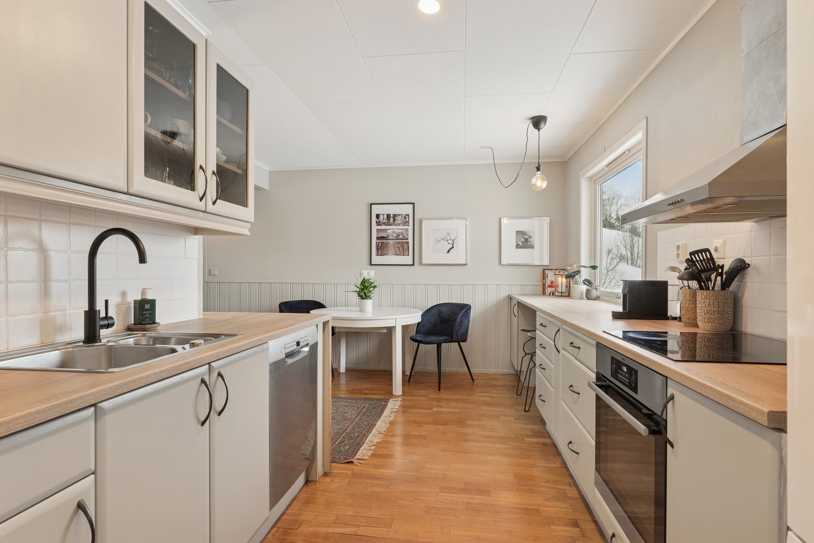 Kjøkkenet har en innredning med glatte fronter, enkelte overskap med glassfronter og en benkeplate i laminat. Galleribilde