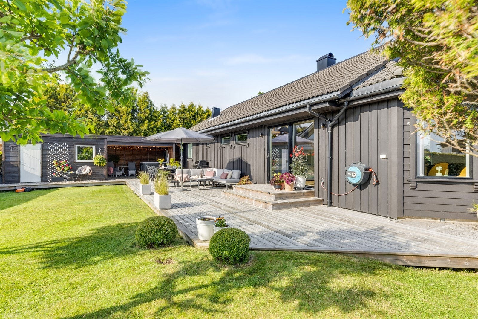 Stor solrik vestvendt terrasse som strekker seg rundt hele huset Galleribilde