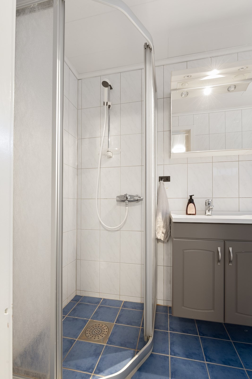 Badet er innredet med dusjhjørne med skyvedører, servantinnredning og gulvmontert toalett Galleribilde