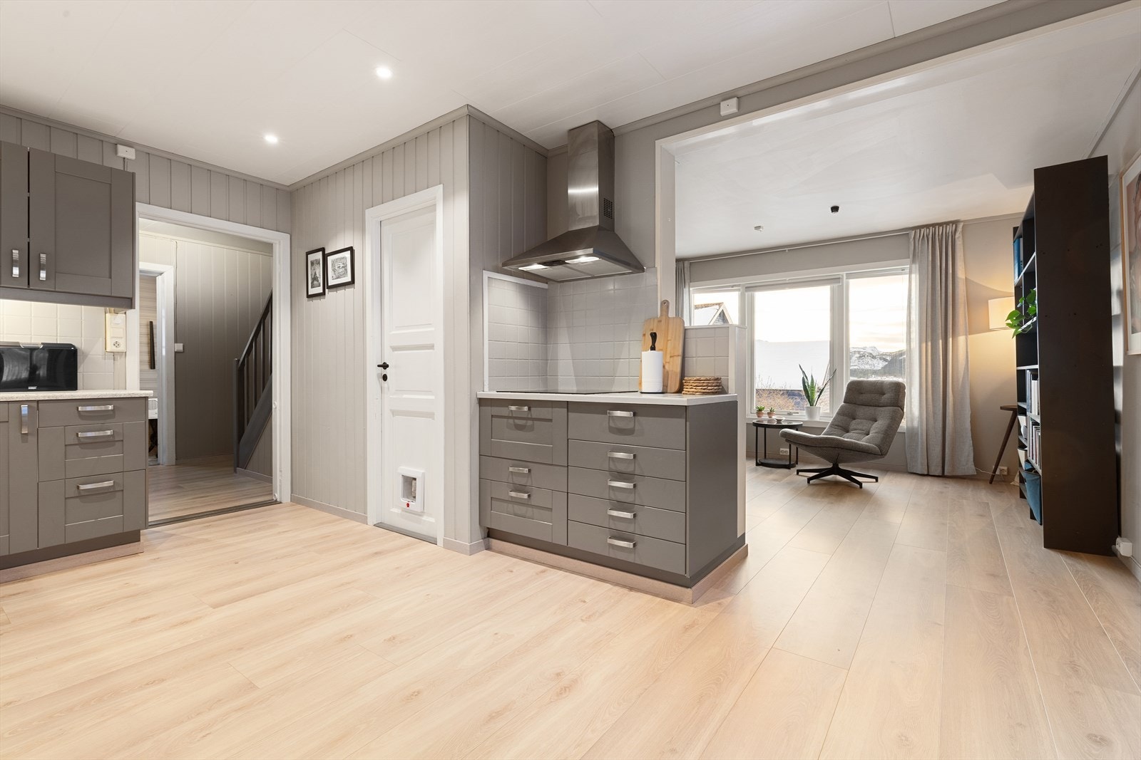 Pent og funksjonellt kjøkken med innredning med speildørsfronter i bjørk, laminat benkeplate og flislagt benk ved platetopp Galleribilde