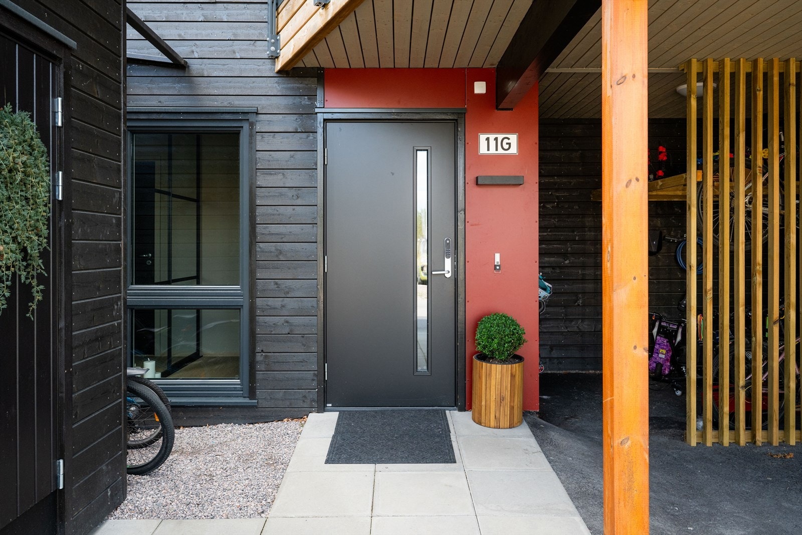 Ved boligens inngangsparti er det asfaltert gårdsplass og carport, med tilliggende åpen bodplass for oppbevaring av sykler m.m. Romslig frittstående bod med god oppbevaringsplass. Det er montert el-bil lader innerst i carport, av merket Easee. Galleribilde