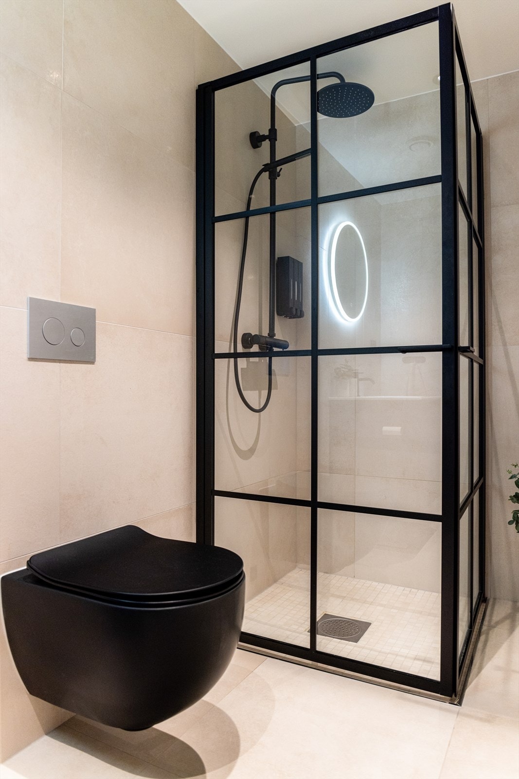 Badet er innredet med servantskap, nedsenket dushjørne og veggmontert toalett, alle i sort utførelse. For øvrig down-light belysning i tak. Galleribilde