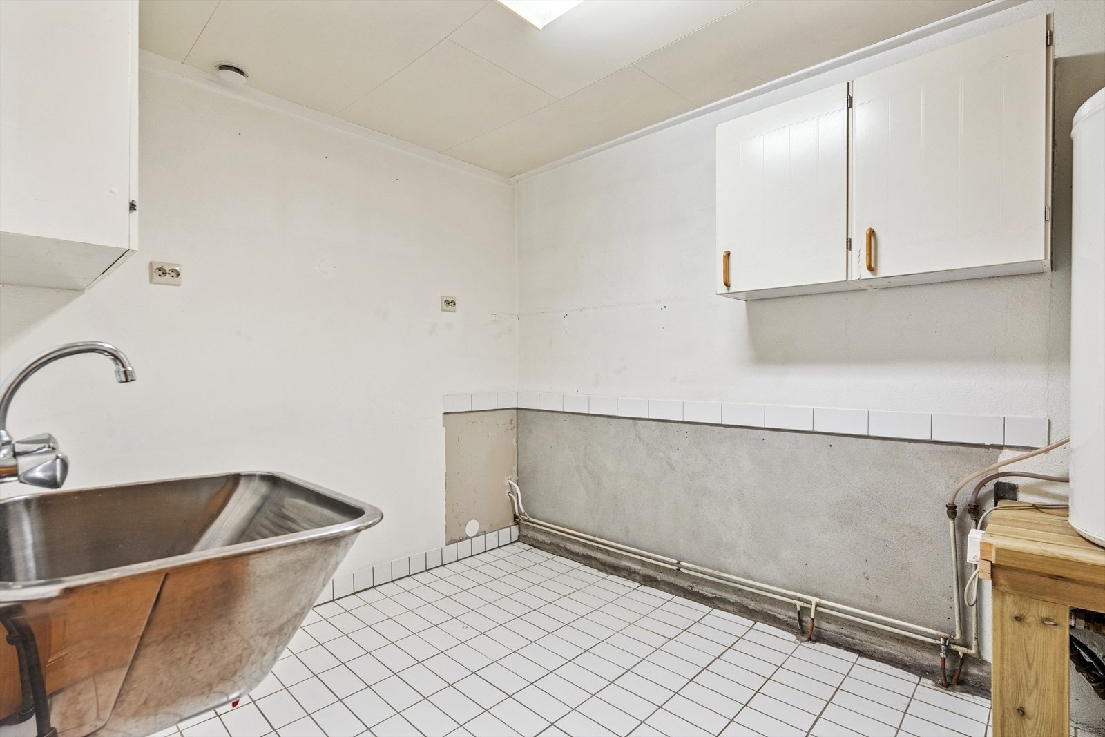 Kombinert vaskerom/teknisk rom har opplegg for vaskemaskin, varmtvannsbereder og rustfritt vaskekar. Her er det støpte gulv med fliser og malte veggoverflater. Galleribilde