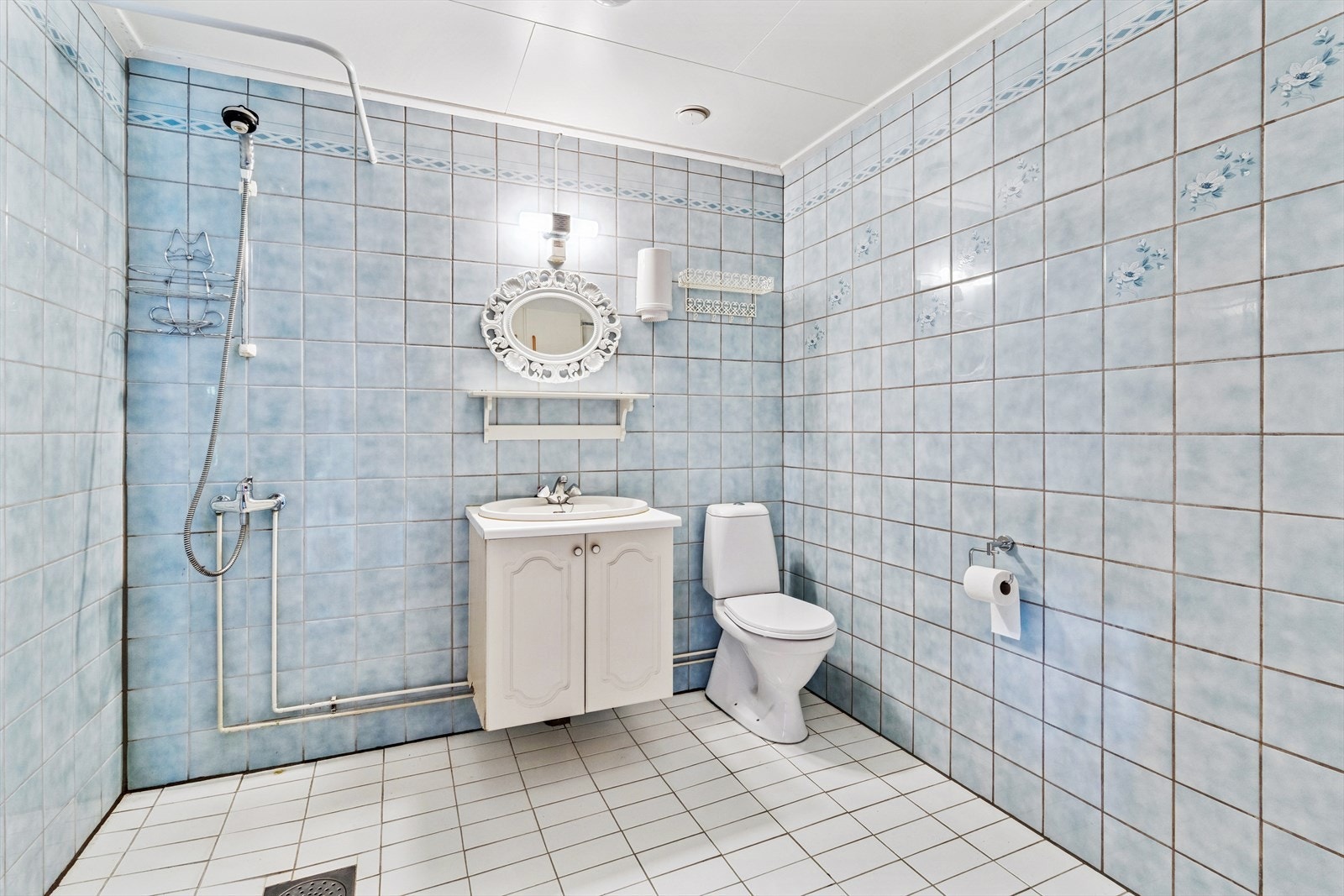 Badet i kjeller har støpt gulv med fliser og flislagte vegger. Rommet er utstyrt med dusjnisje med forheng, servantskap og gulvmontert toalett. Galleribilde