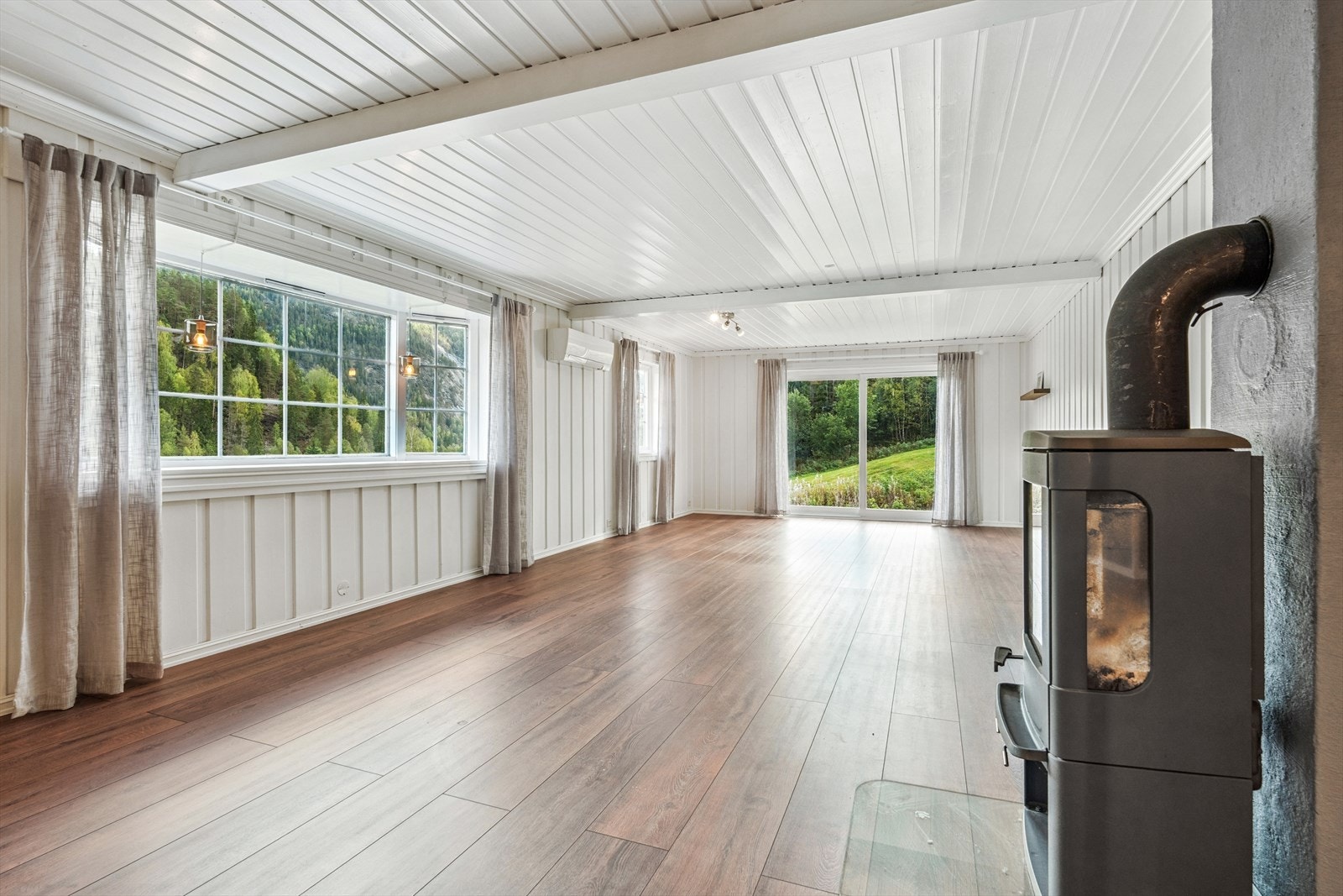 Innenfor møtes du av en lys og romslig stue med synlige dragere i taket. Store vindusflater slipper inn mye naturlig lys og gir flott utsyn mot uteområdet. Galleribilde