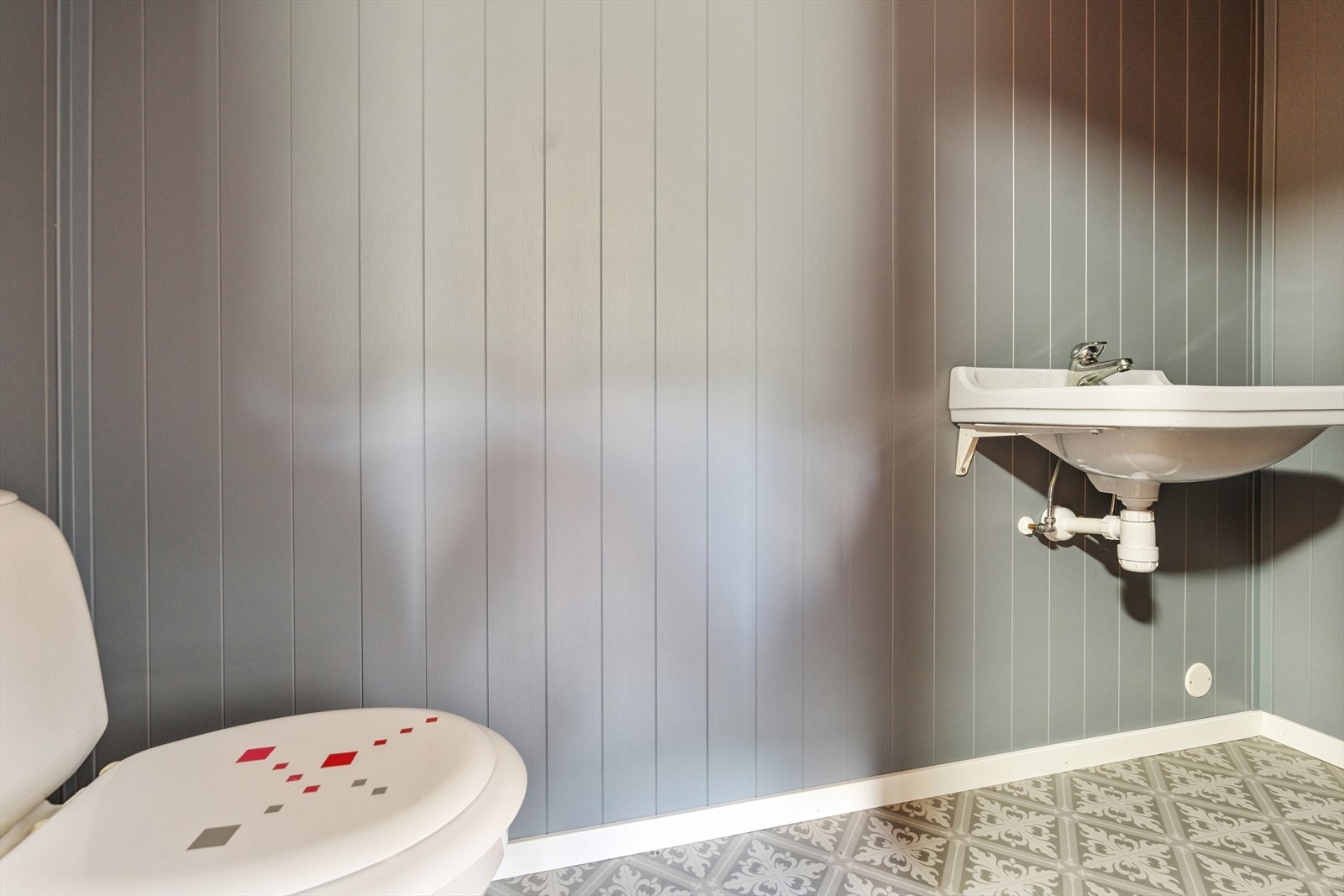 Eget toalettrom med gulvmontert toalett og vegghengt servant. Galleribilde