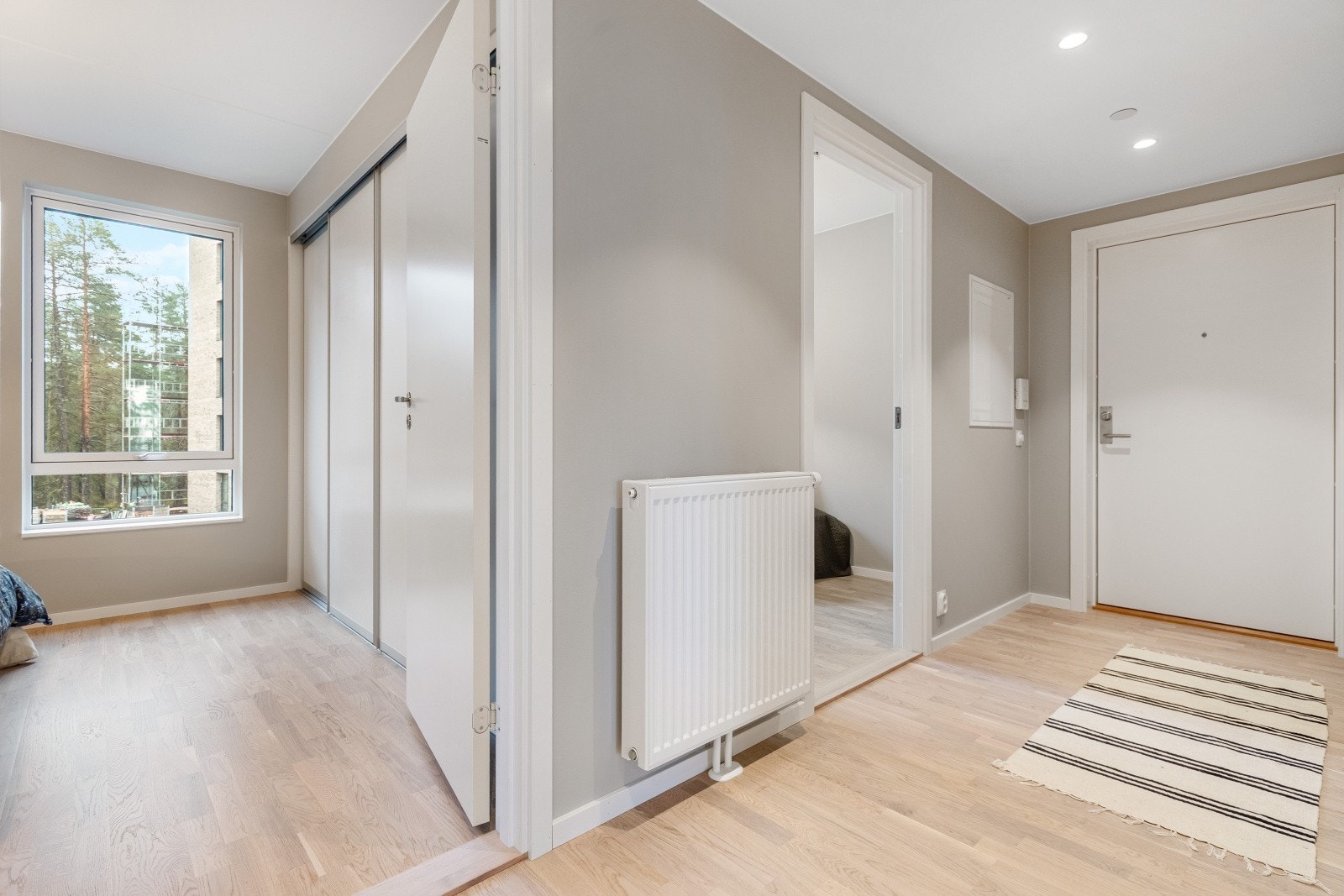 Tilbake i entreen fordeler gangen seg til begge soverommene og badet. Denne praktiske planløsningen gir en god flyt i boligen og gjør det enkelt å navigere mellom rommene. Galleribilde