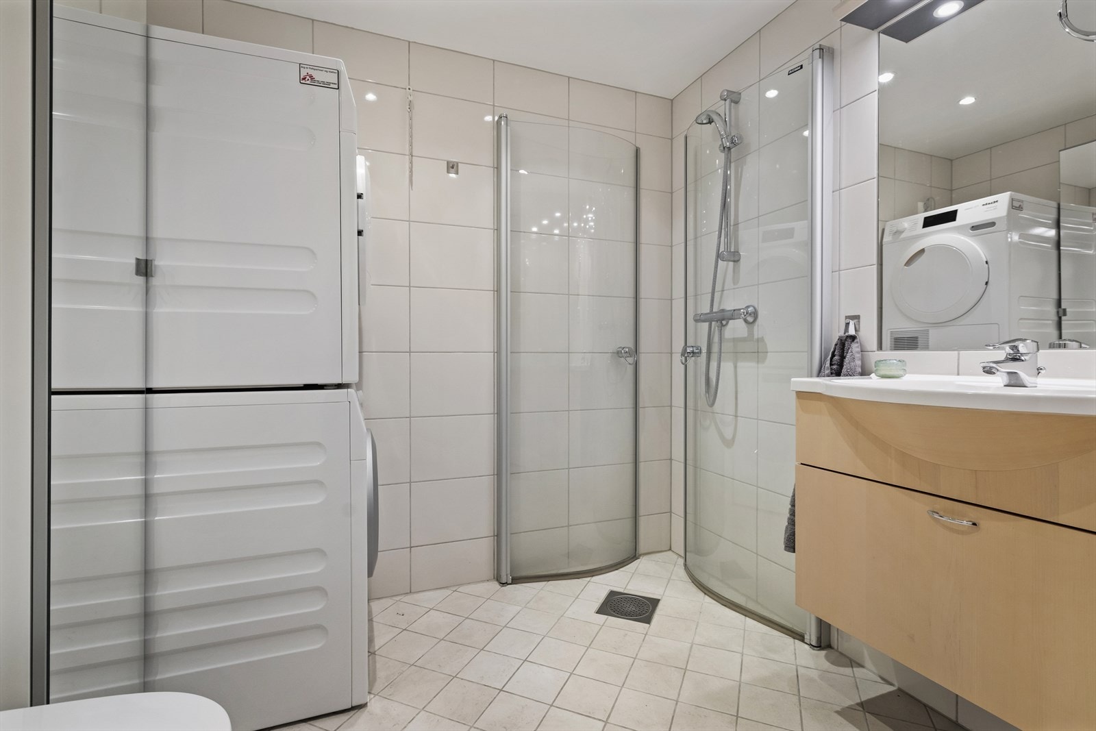 Pent bad/wc/vaskerom med underskap og servant. Innfelt speil på vegg over servant. Nyere lysbaldakin over servant. Veggmontert toalett med innebygget sisterne. Dusjnisje med glassdører. Opplegg til vaskemaskin/tørketrommel Galleribilde