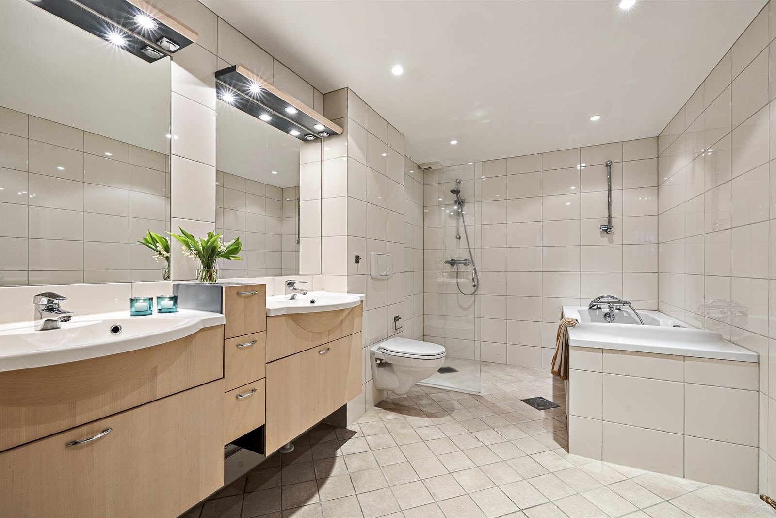Pent bad/wc med innredning med to nedfelte servanter. Nyere lysbaldakiner over servantene. Veggmontert toalett. Innbygget badekar. Nyere dusjdører og blandebatteri. Støpt og flislagt gulv med varmekabler, flislagte vegger Galleribilde