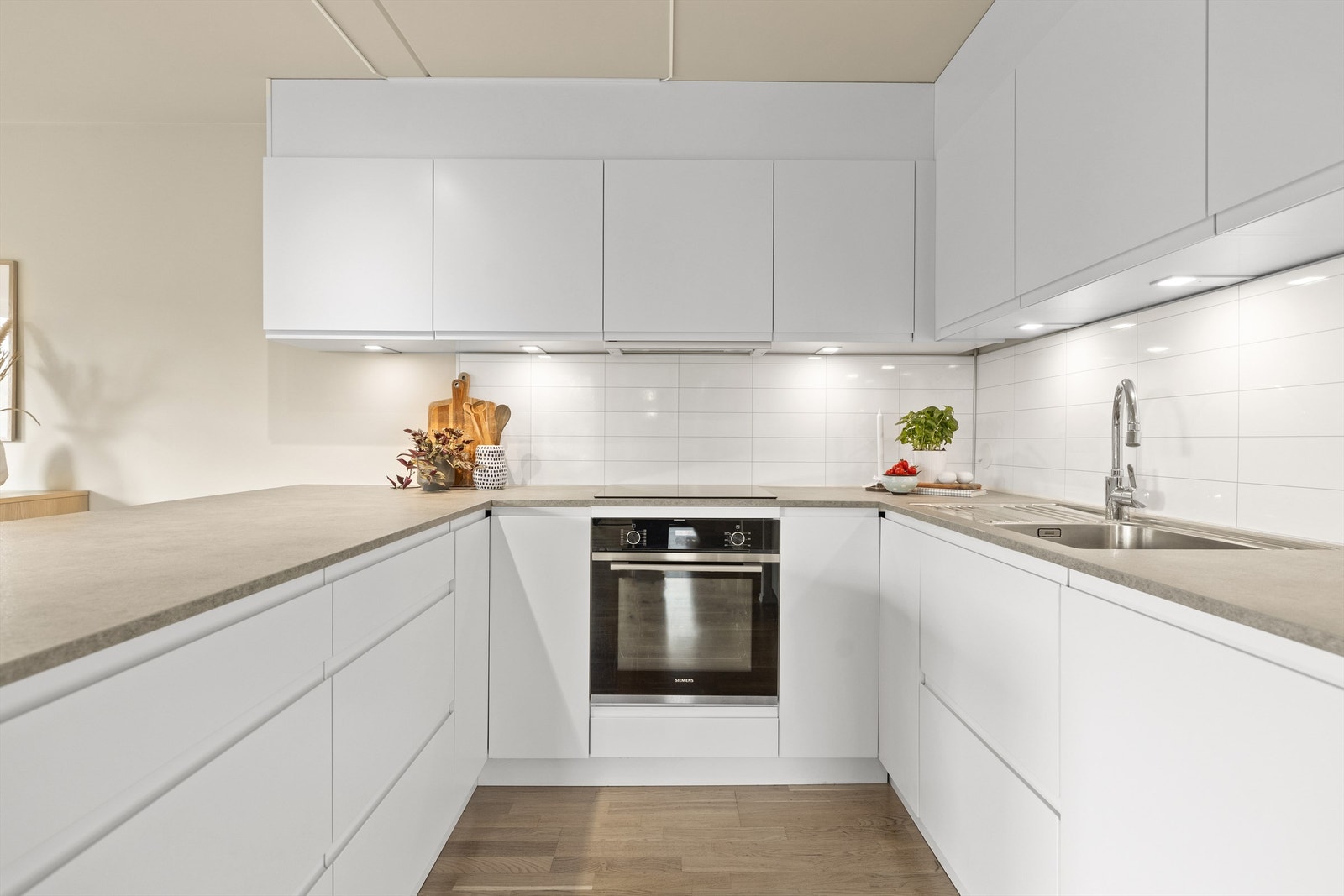 Flott Kvik kjøkkeninnredning fra 2021/2022 med slette fronter og benkeplater av laminat. Integrerte hvitevarer stekeovn, platetopp, oppvaskmaskin og kjøleskap med fryser Galleribilde