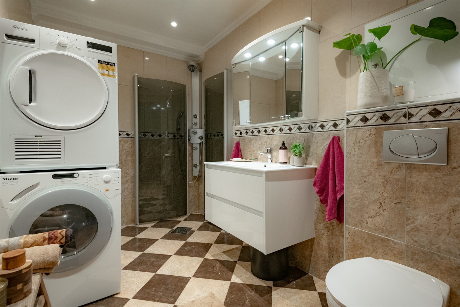 Romslig og pent flislagt bad varmekabler og opplegg for vaskemaskin og tørketrommel. Galleribilde