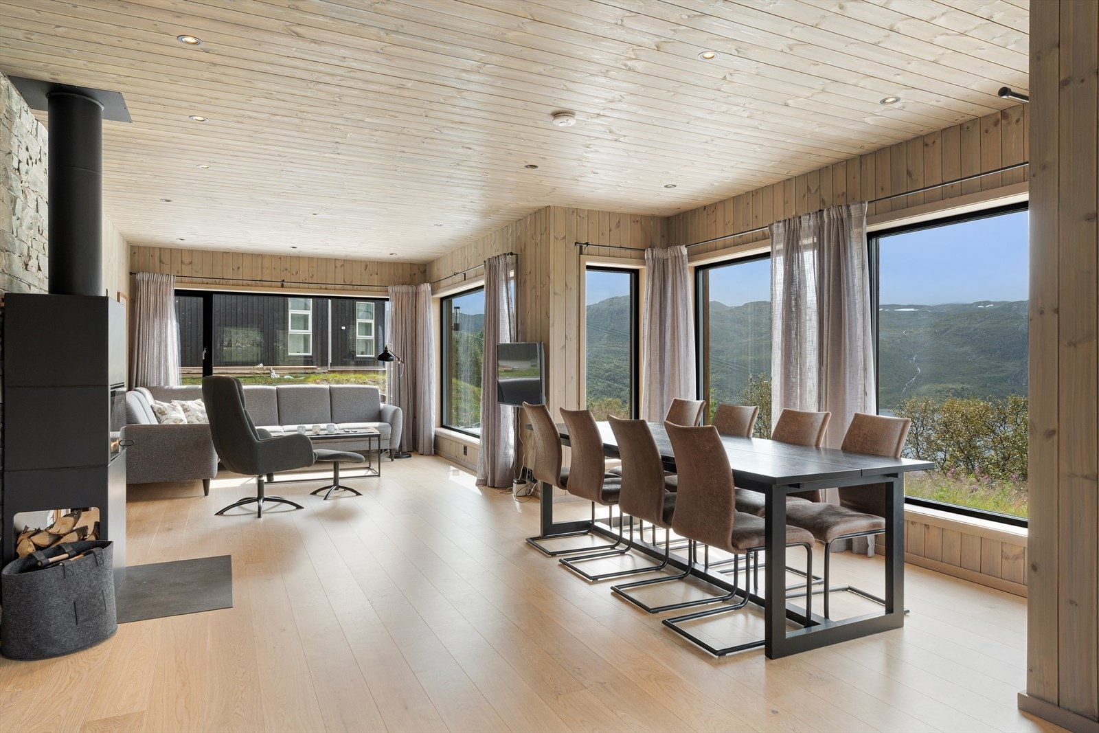 Lys og innbydende stue med store vindusflater Galleribilde