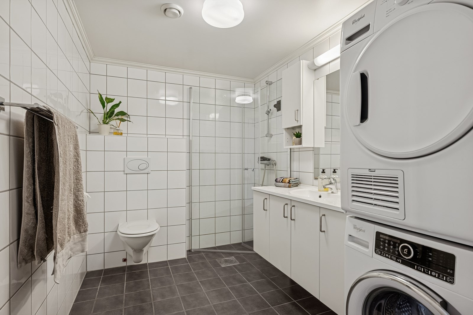 Leiligheten har et romslig bad med varmekabler i gulvet, vegghengt toalett og et dusjhjørne som ble oppgradert i 2026. Galleribilde