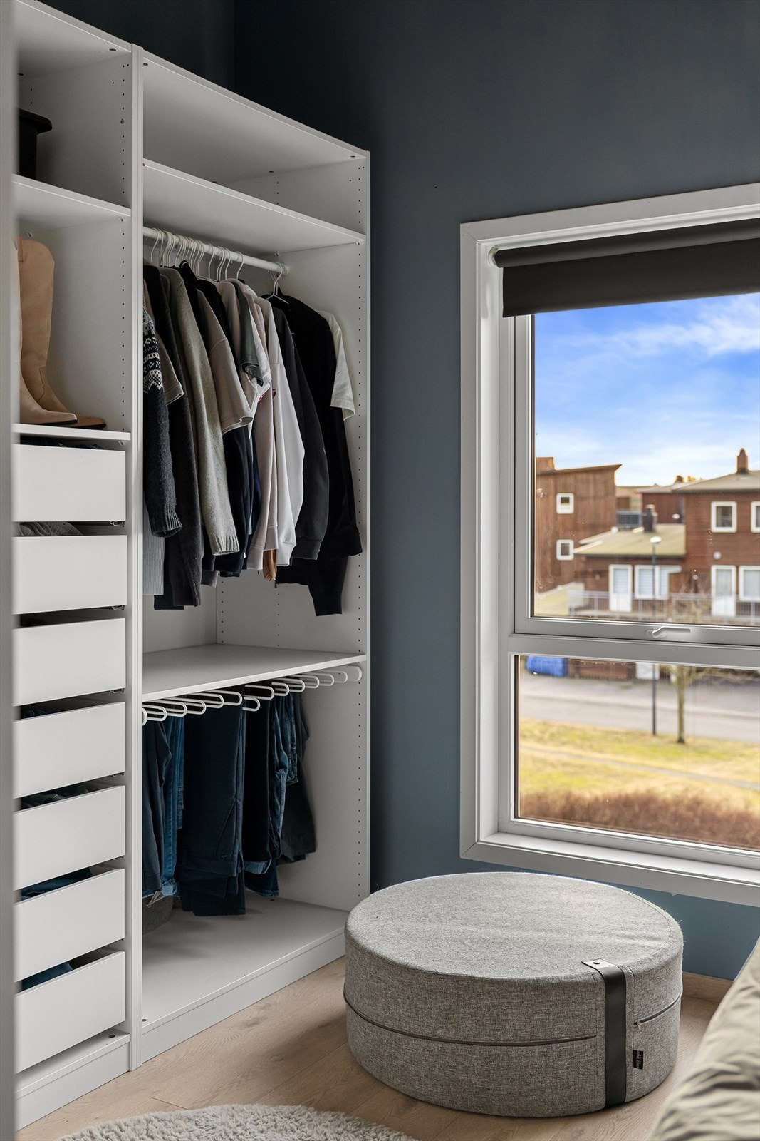 Lyst og moderne walk-in closet med store vinduer som gir naturlig lys. Praktisk oppbevaring og stilren innredning. Galleribilde