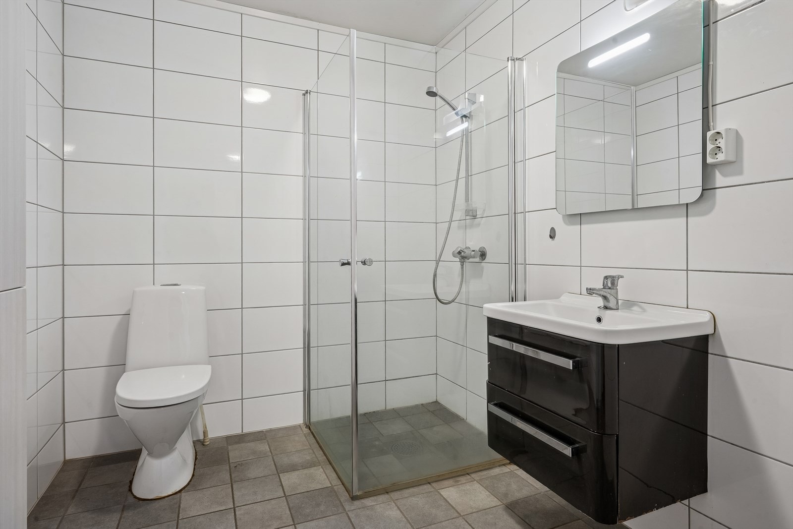 Badet i den andre enheten er utstyrt med dusjhjørne og servantmøbel. Galleribilde