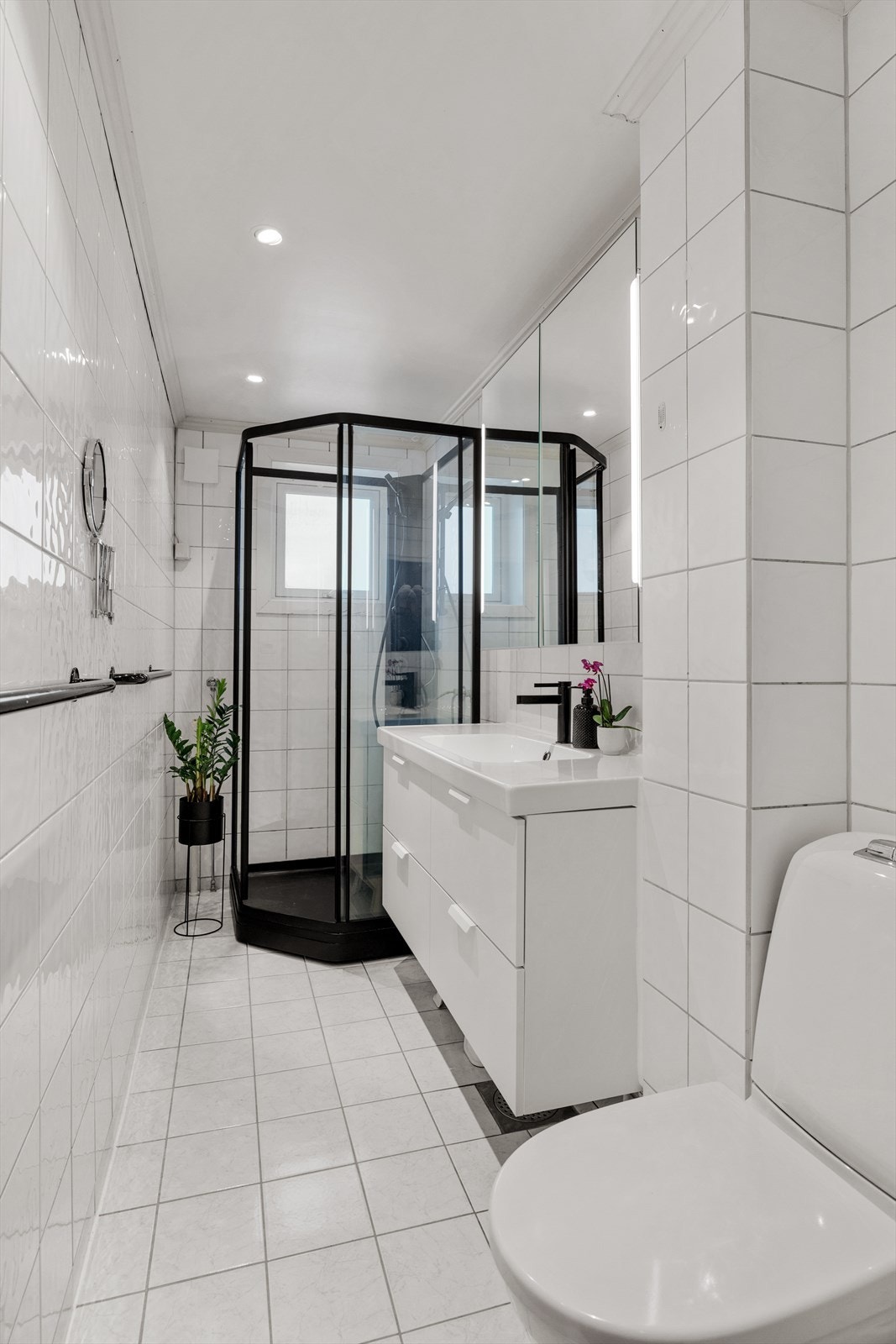 Badet er utstyrt med dusjkabinett, servant med underskap, speilskap med lys og wc. Galleribilde