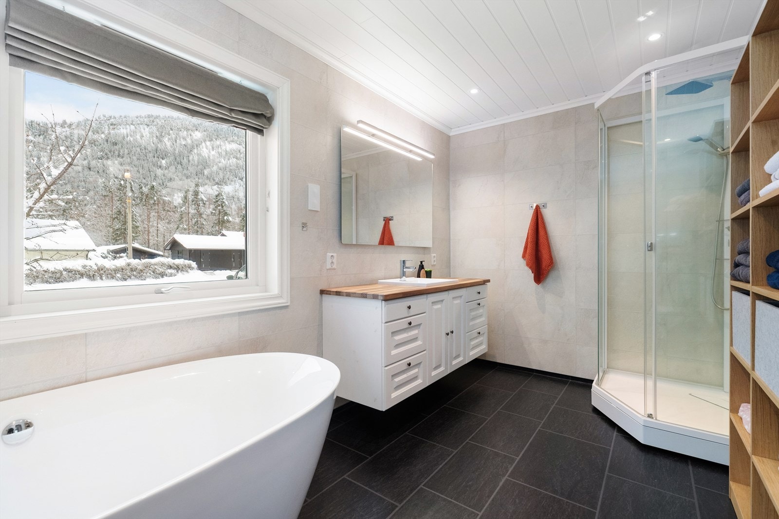 Delikat bad fra 2016 med vinylbelegg på gulv og baderomsplater på vegger. Her er det dusjkabinett og romslig innredning med benkeplate og nedfelt vask, underskuffer og skap med profilerte fronter. Speil og lys. Galleribilde