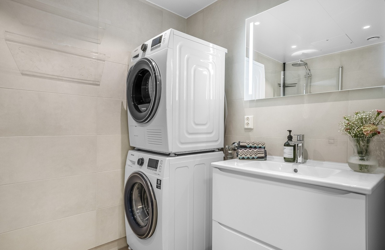 Badet fremstår lekkert med vegghengt toalett og opplegg for vaskemaskin og tørketrommel. Galleribilde