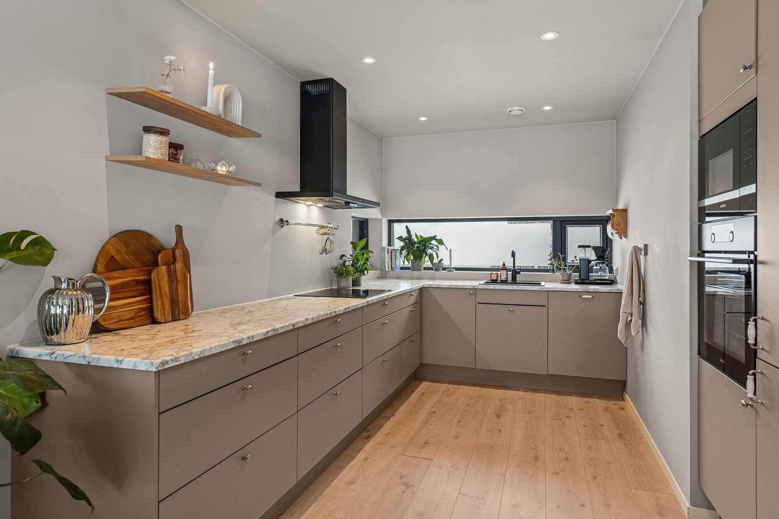 Den stilrene innredningen har moderne glatte fronter, laminat benkeplate og nedfelt oppvaskkum Galleribilde