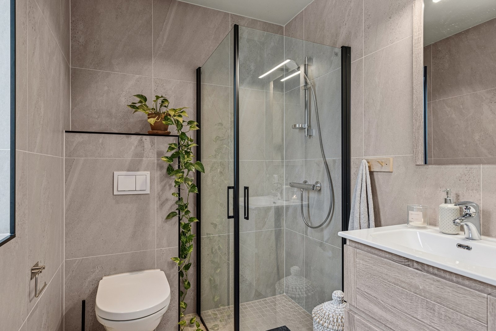 Baderom med innfelte downlights, gulvvarme og en innredning med glatte fronter og praktisk oppbevaring i skuffeseksjon Galleribilde