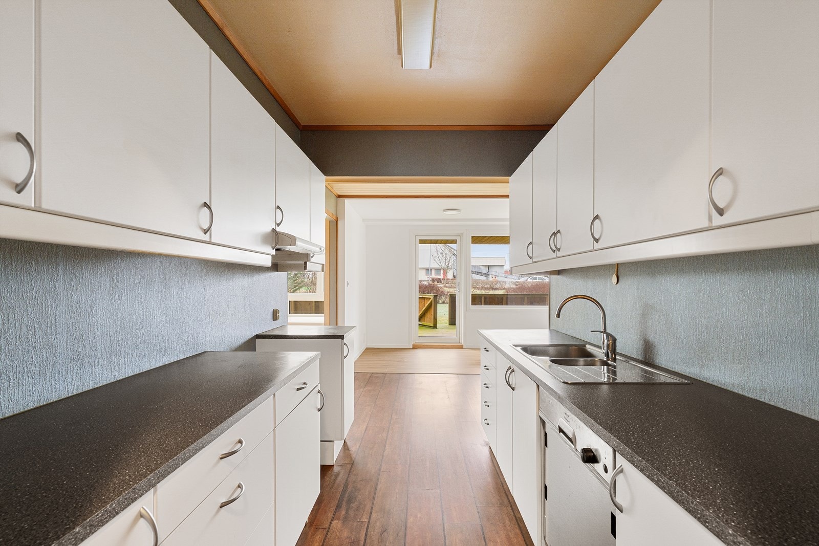 Kjøkken med hvite fronter og mørke benkeplate. Galleribilde